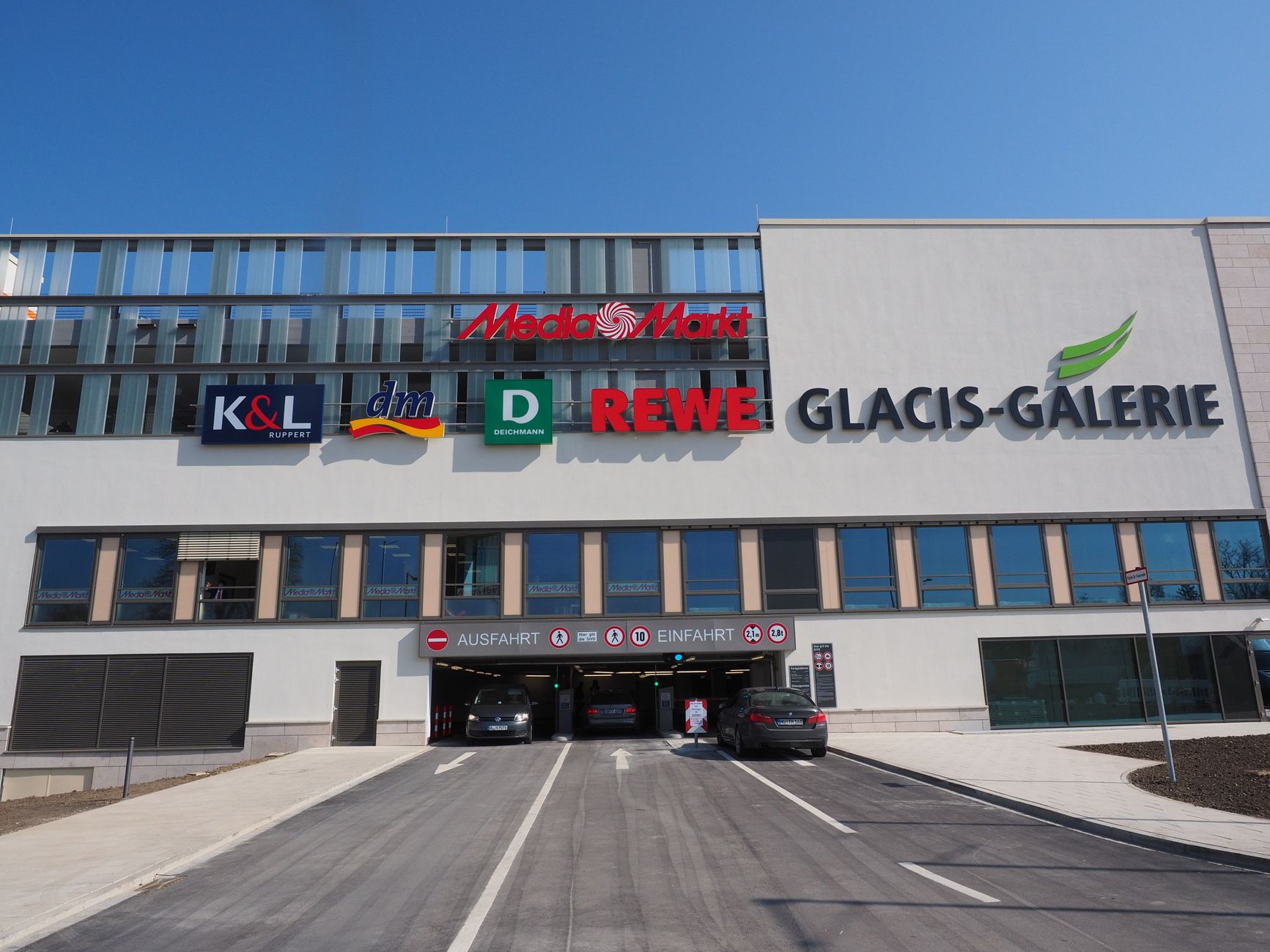 An open-air outlet center with broad parking rows and storefronts at dusk, showing the large exterior area that must be covered after close.