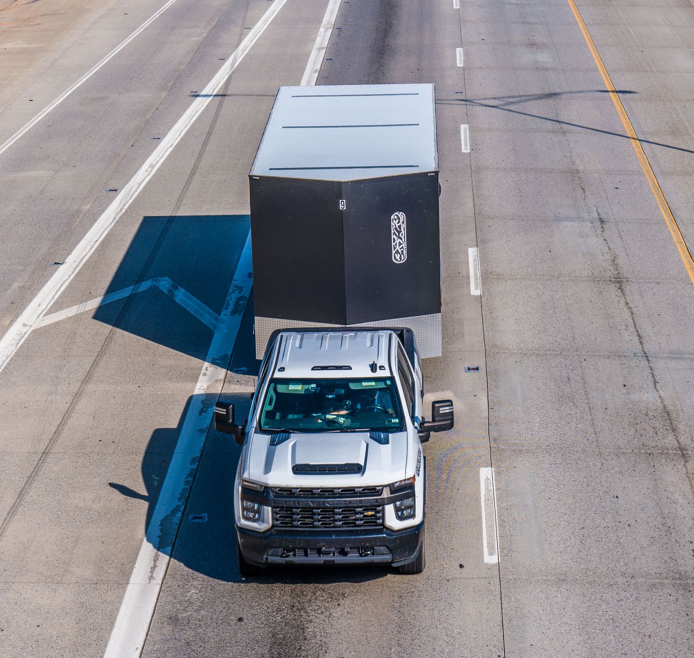 Customer pickup lane with trucks and trailers staged near a fenced equipment sales lot.