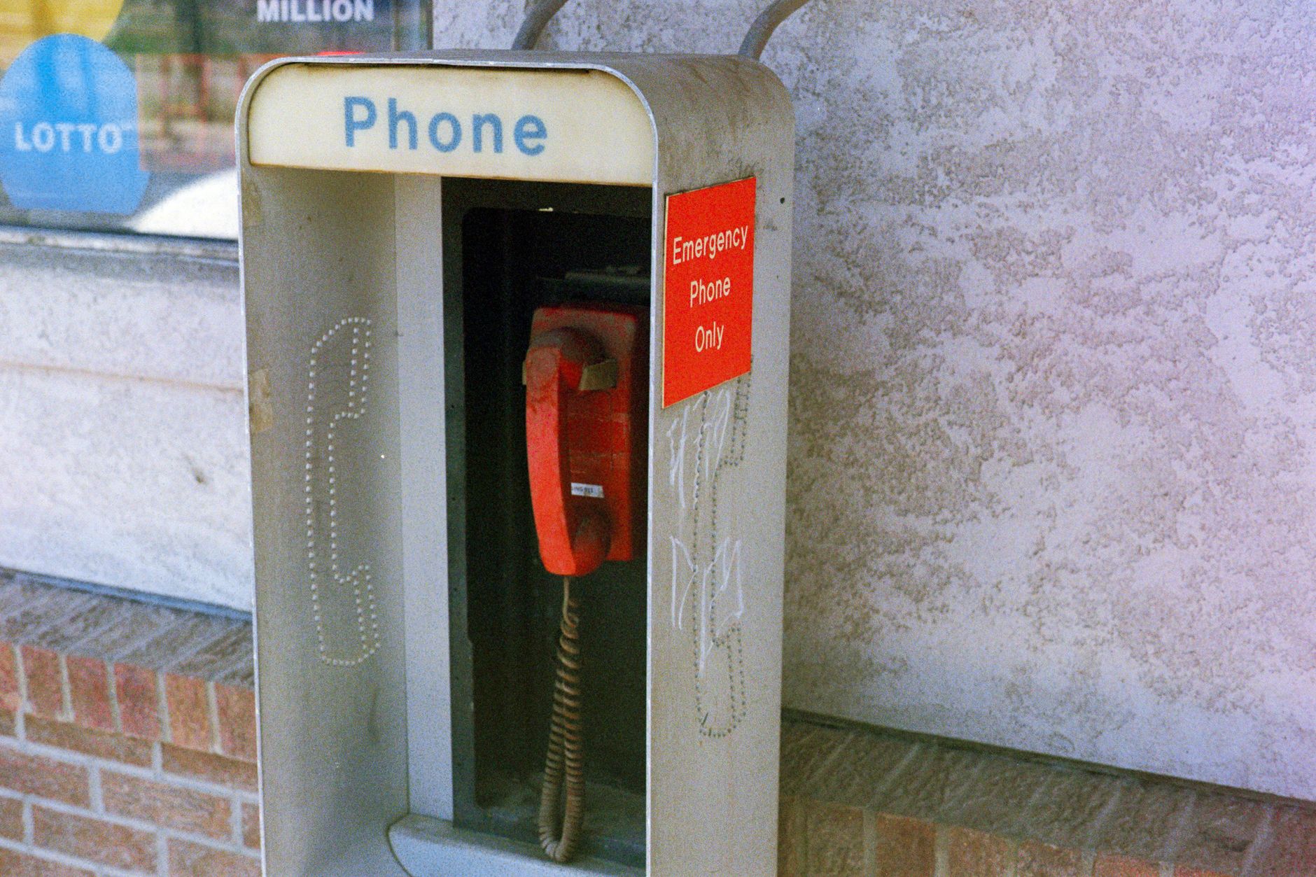Blue emergency call station beside a sidewalk near a transit facility.