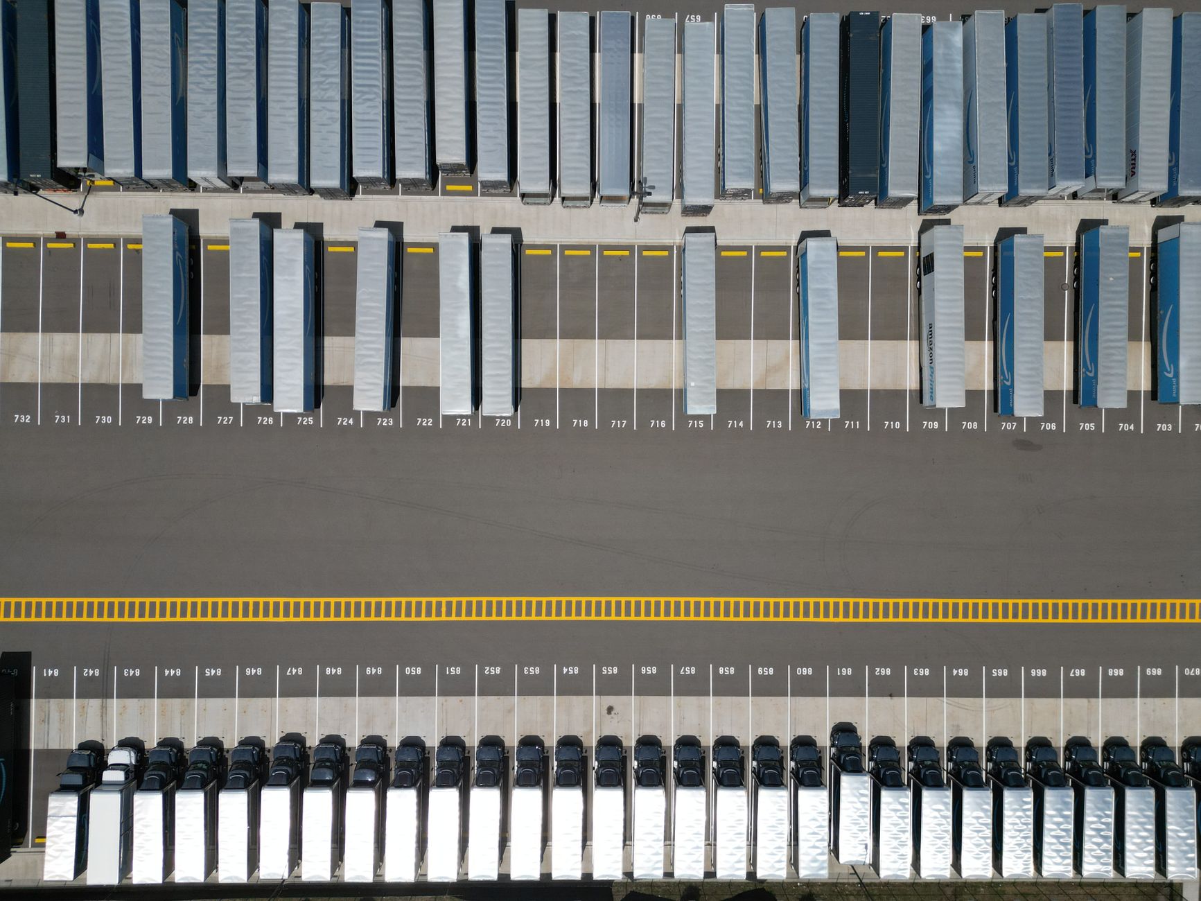 A large pharmaceutical distribution warehouse with loading docks and cargo trailers in its receiving yard.
