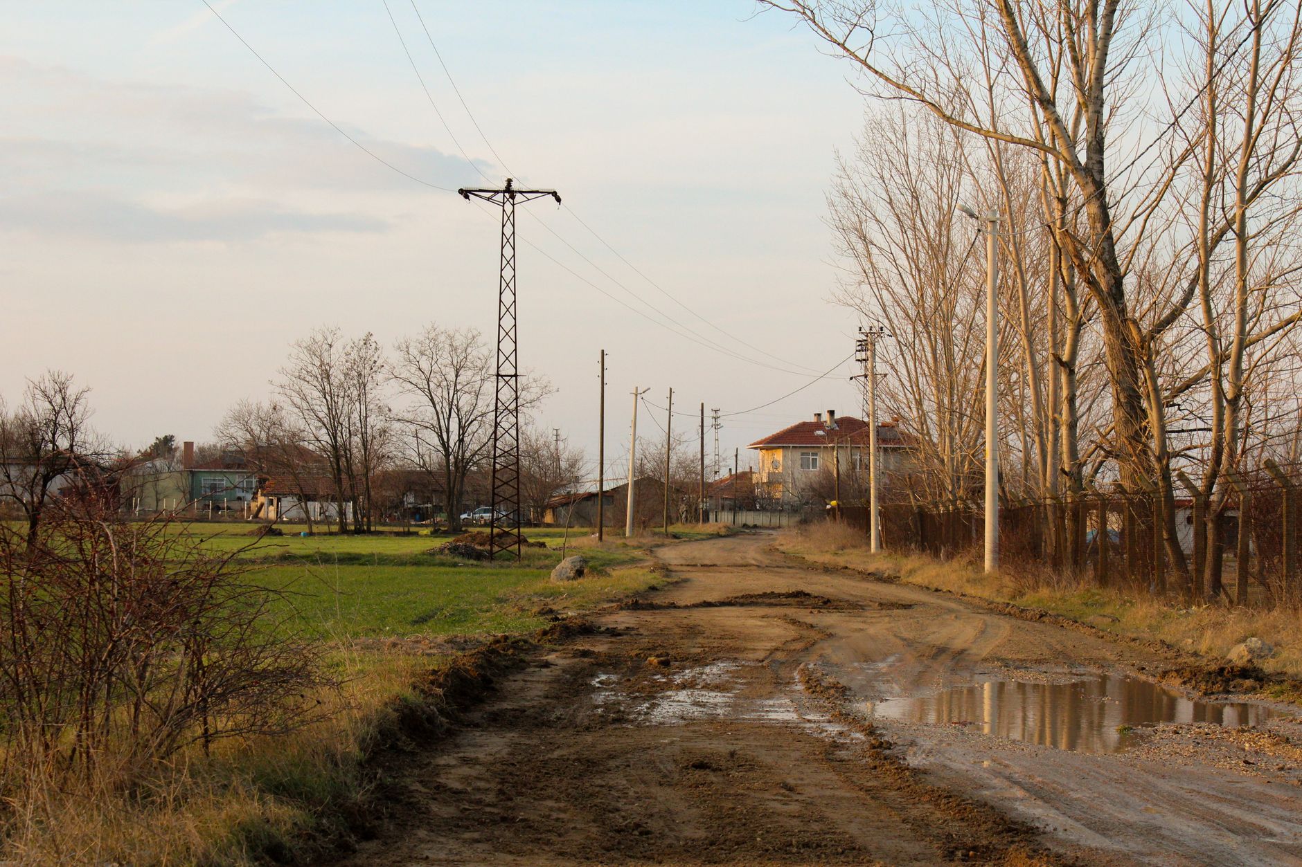 Wet gravel and mud on a service road, showing footing risks for outdoor patrol units after storms.