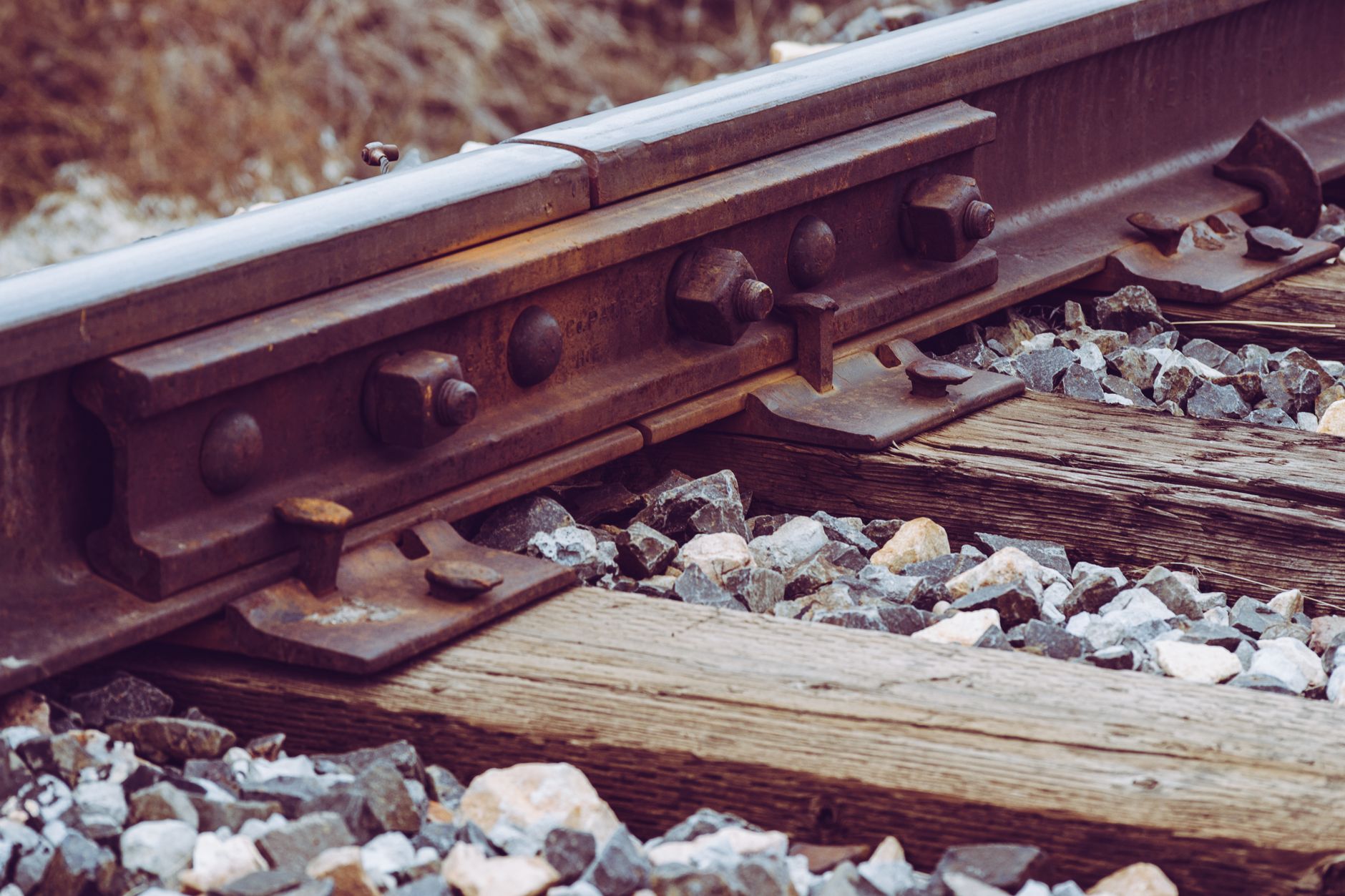 Angular ballast surrounds steel rails and highlights the rough terrain beside approved patrol lanes.