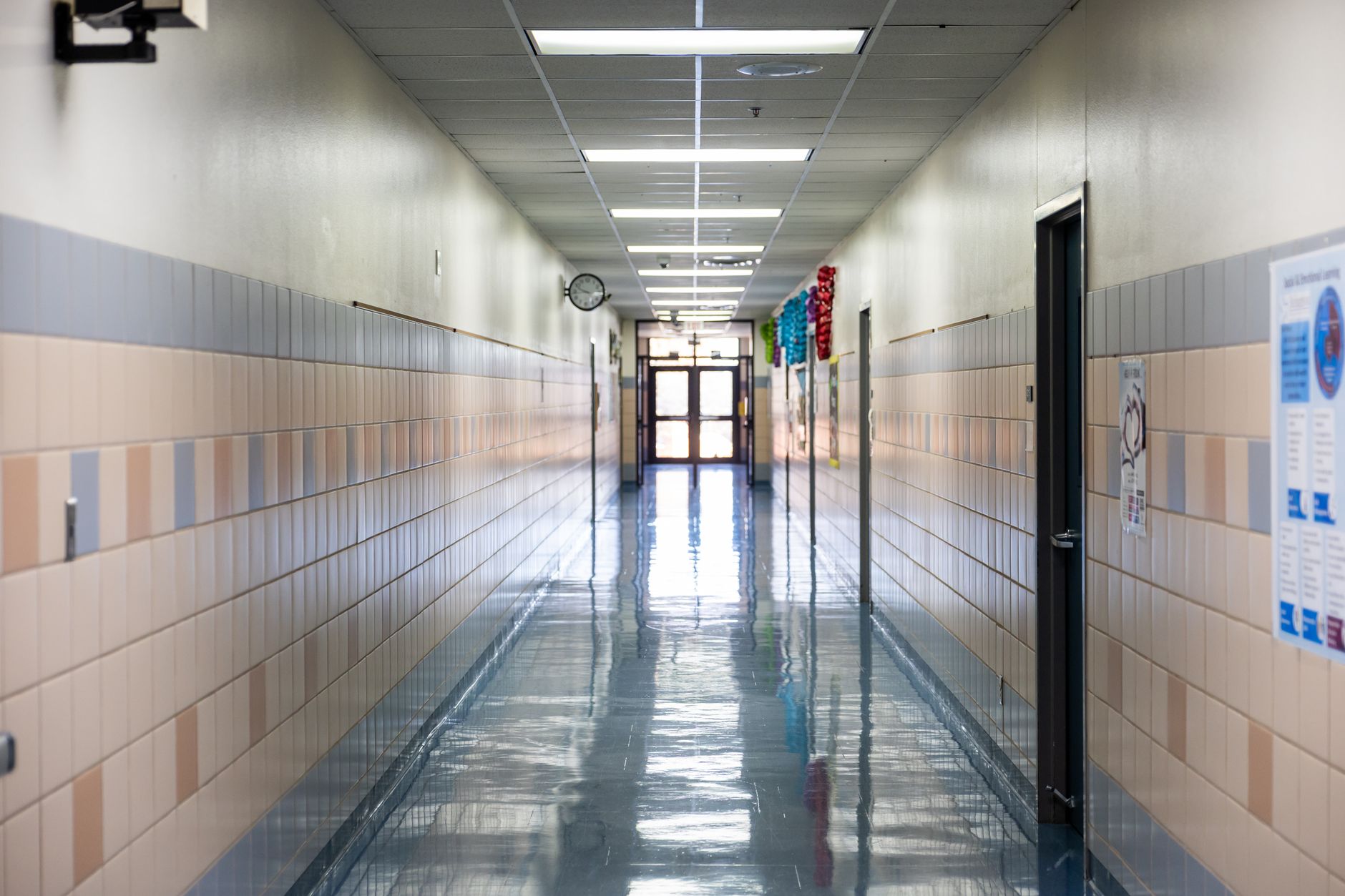 A long, empty corridor inside a self-storage facility, flanked by identical, closed roll-up doors, illustrating the security challenge of monitoring such a space.