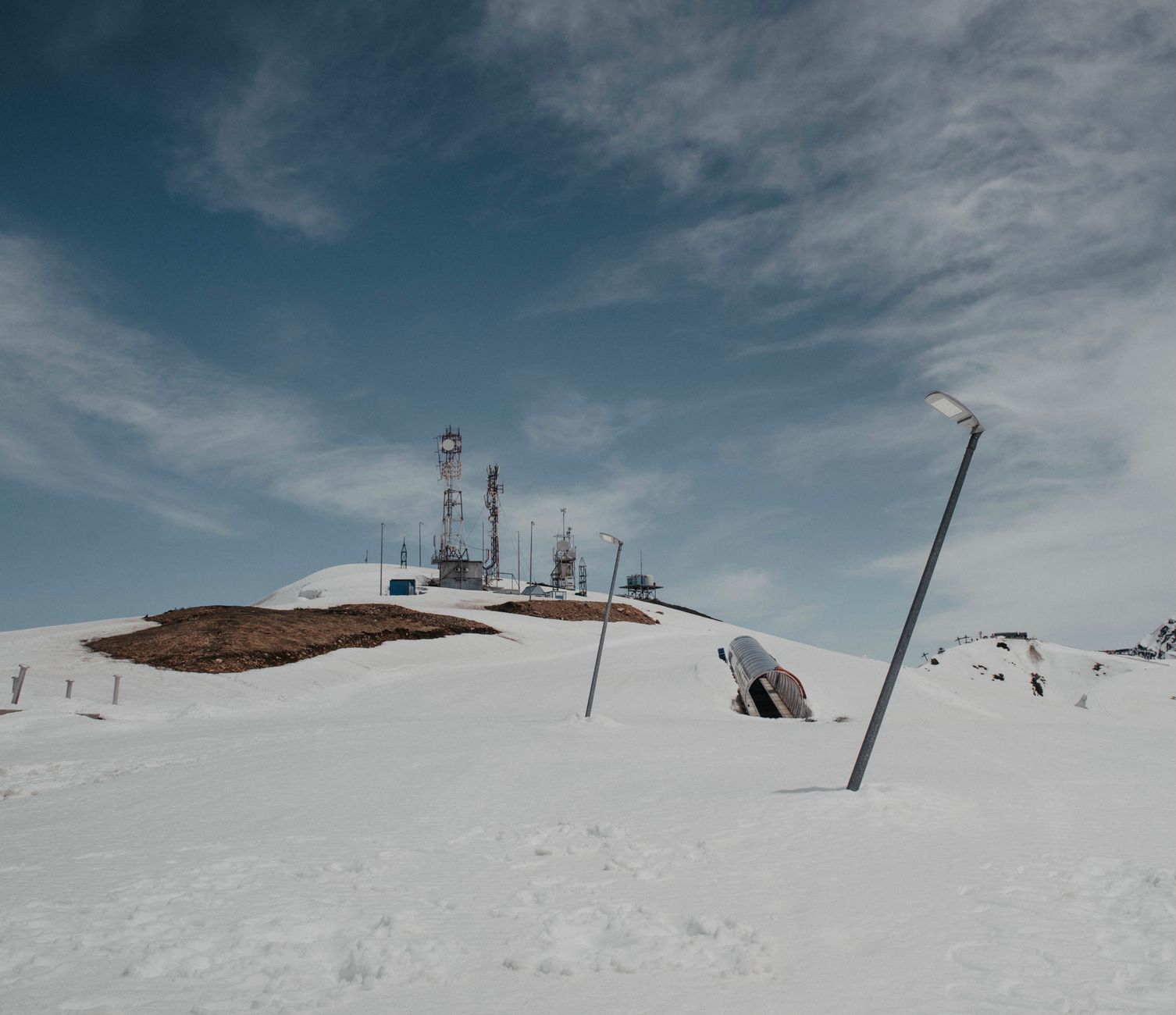 Communications antennas stand above snowy mountain terrain where ridges and buildings can disrupt coverage.