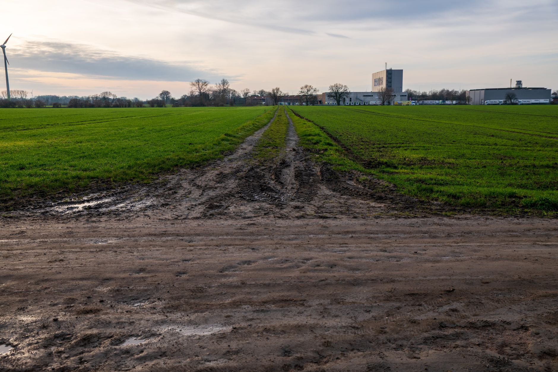 A muddy industrial access road like the lanes patrol robots must climb after rain at a transfer station.