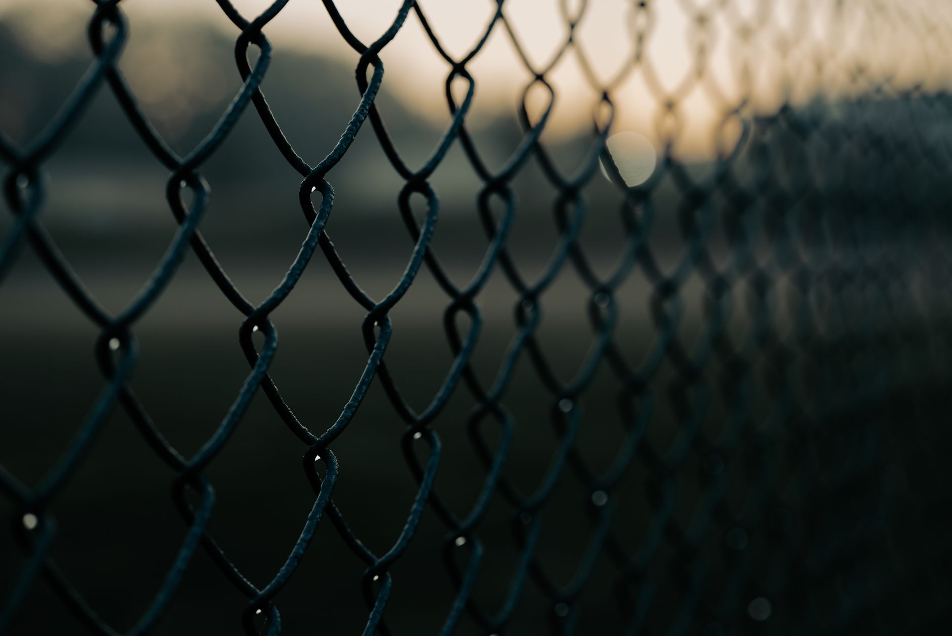 A chain-link perimeter fence line that after-hours patrol routes must monitor for illegal dumping.