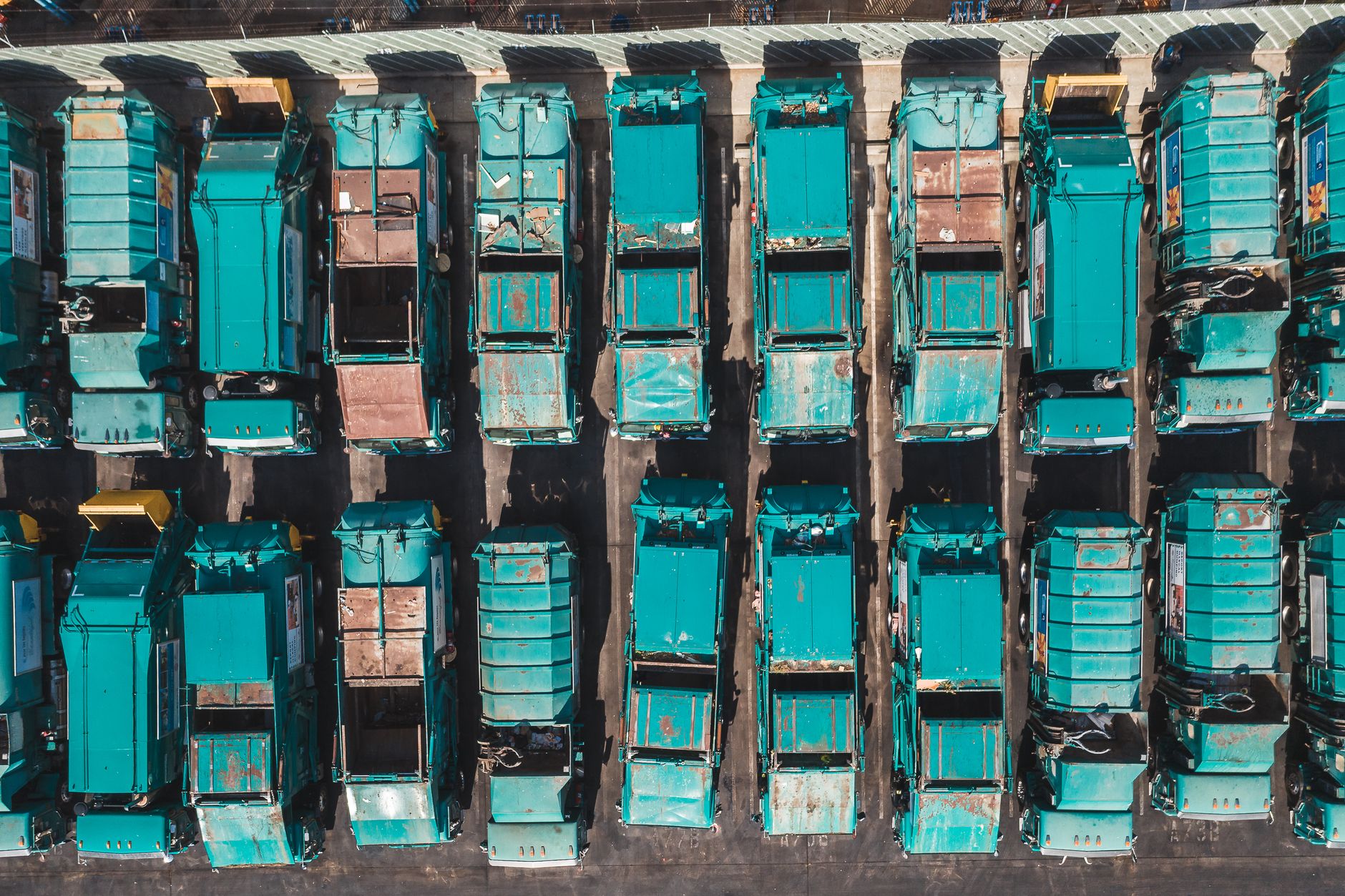 Rear-loading garbage trucks parked at a municipal waste transfer yard at dusk.
