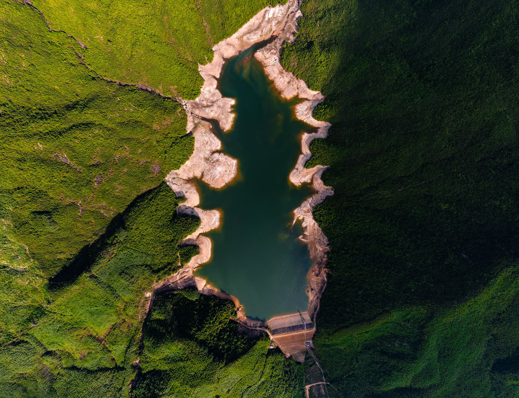 A remote water reservoir with service roads and utility infrastructure around its perimeter.