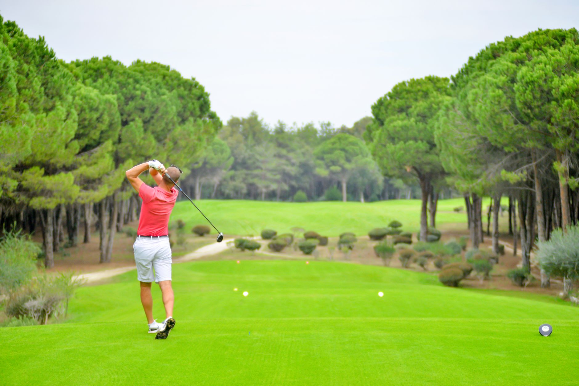 A morning shamble league drive on a fairway where team select-ball play clusters carts on shared corridors.