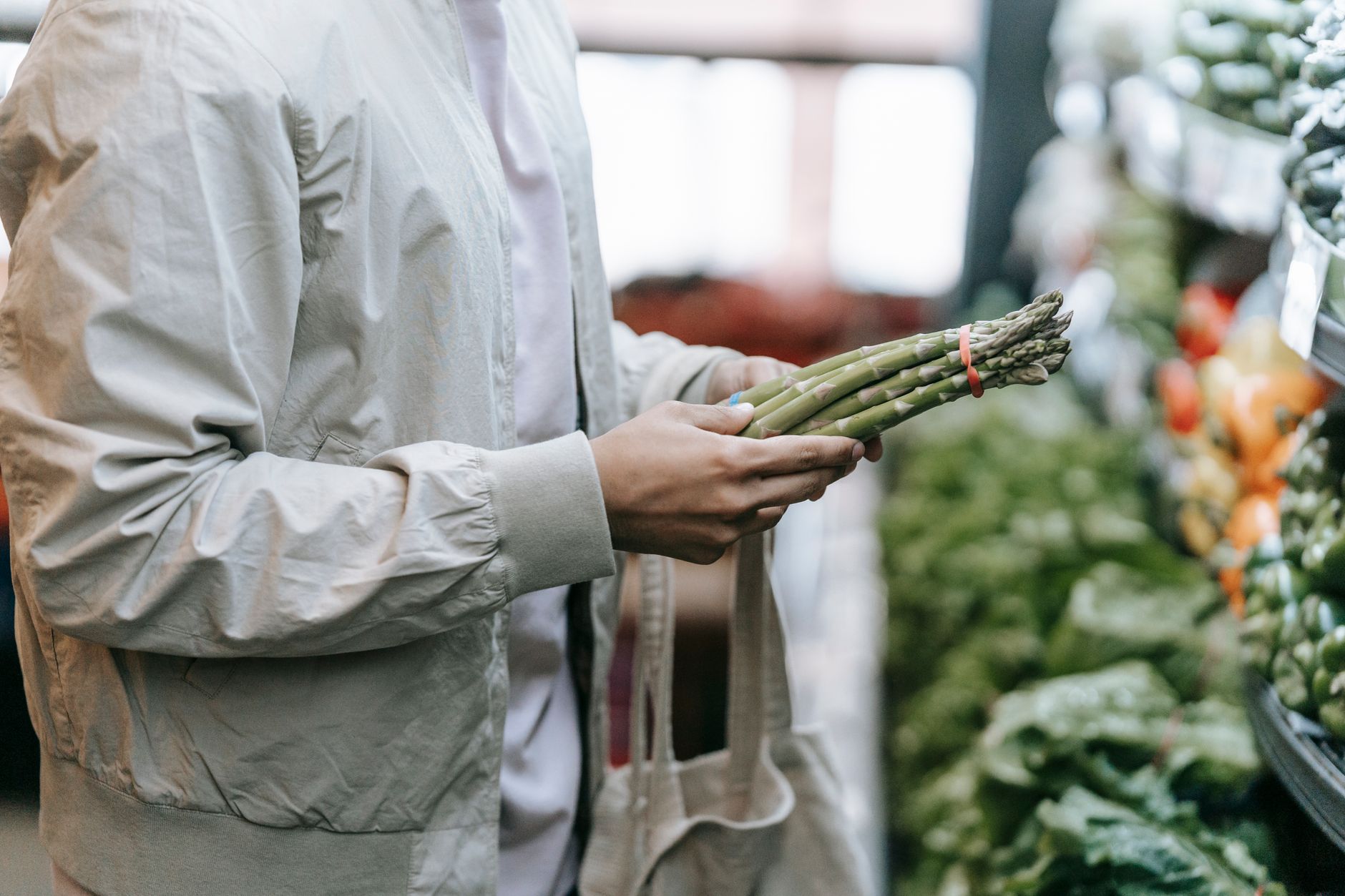 A grocery associate checking produce and shelf conditions, representing the judgment and corrective work people still do better than machines.