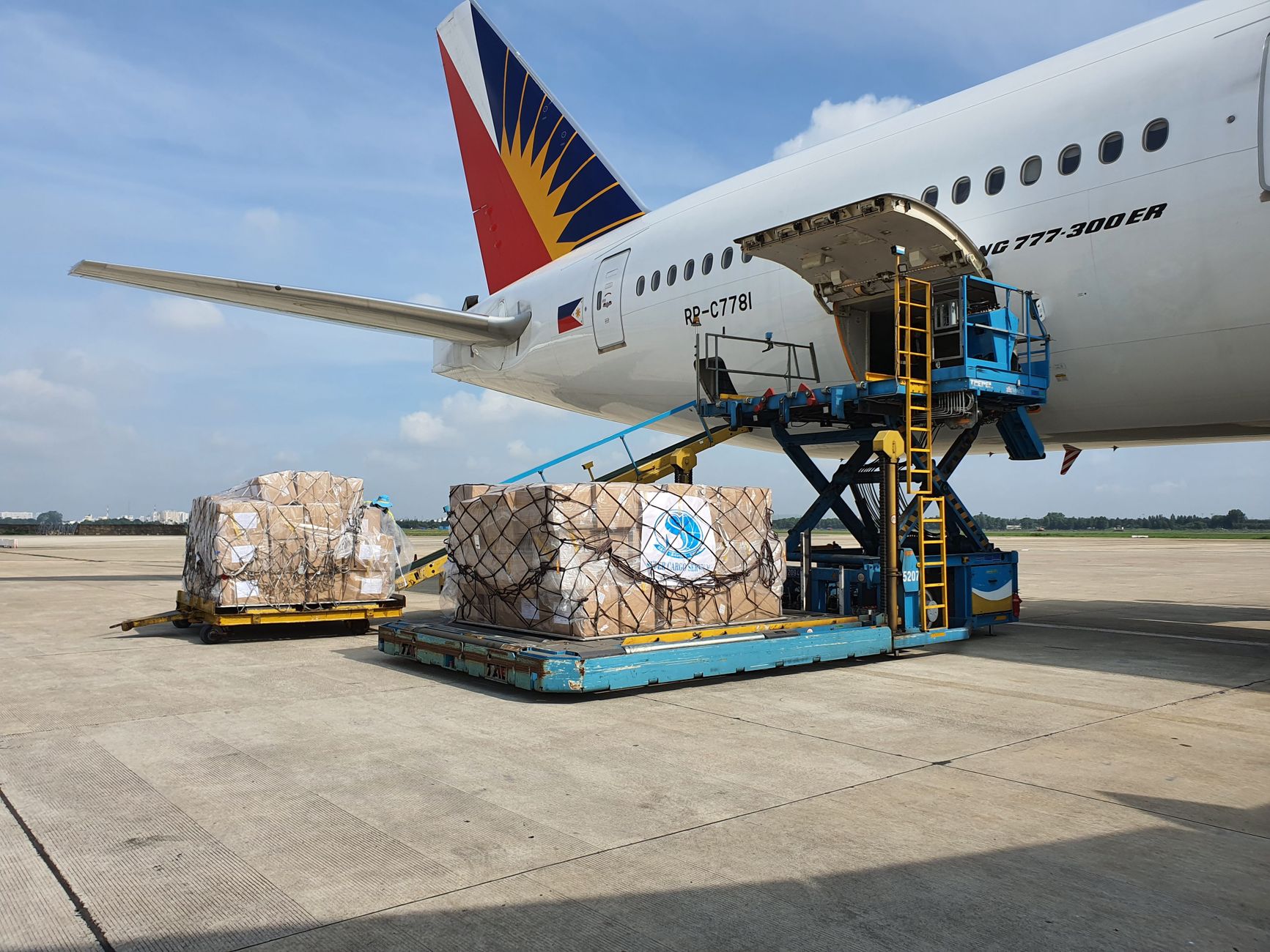 Cargo containers and dollies lined up on the ramp, representing repetitive baggage and cargo moves on defined airport routes.