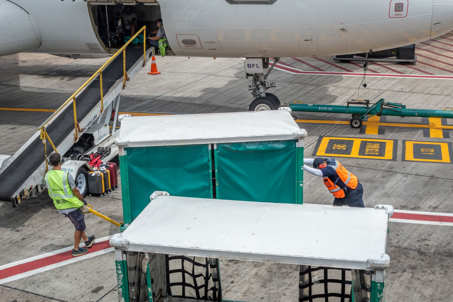 Ground crew working around an aircraft on a busy apron, capturing the mixed-traffic, high-judgment environment operators should automate cautiously.