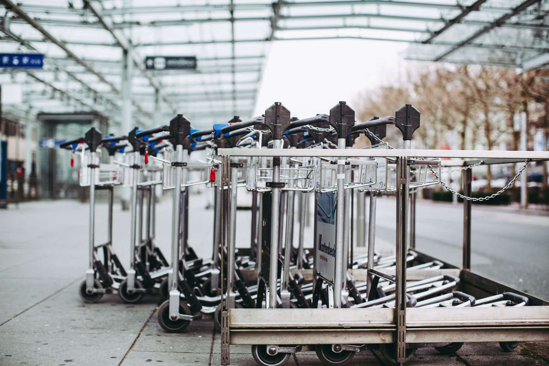 Baggage carts and service vehicles staged on an airport apron before departures, illustrating the repetitive ramp work airports may automate first.