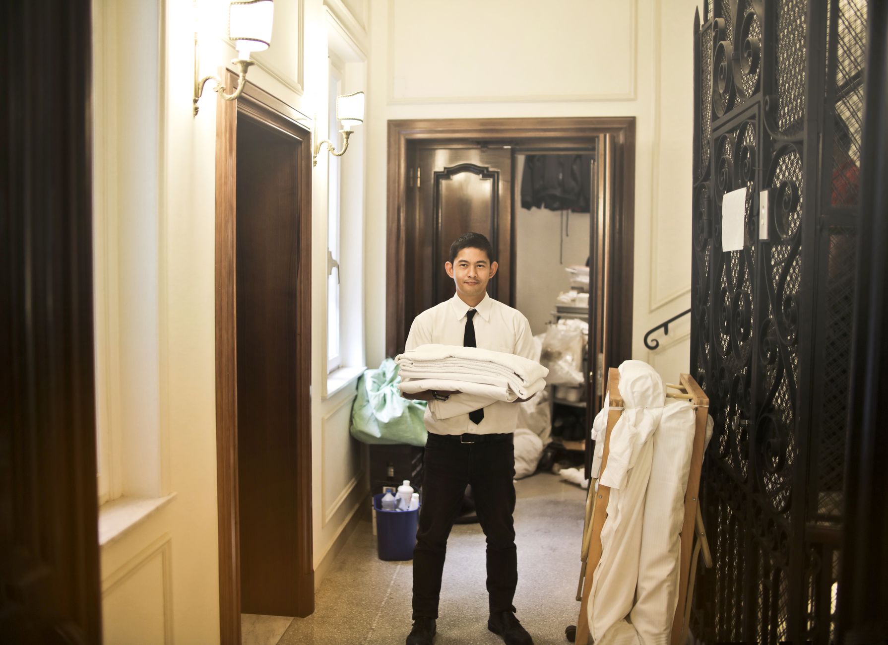 A worker moving a linen cart through a long interior hallway, illustrating the repetitive transport work described in the article.
