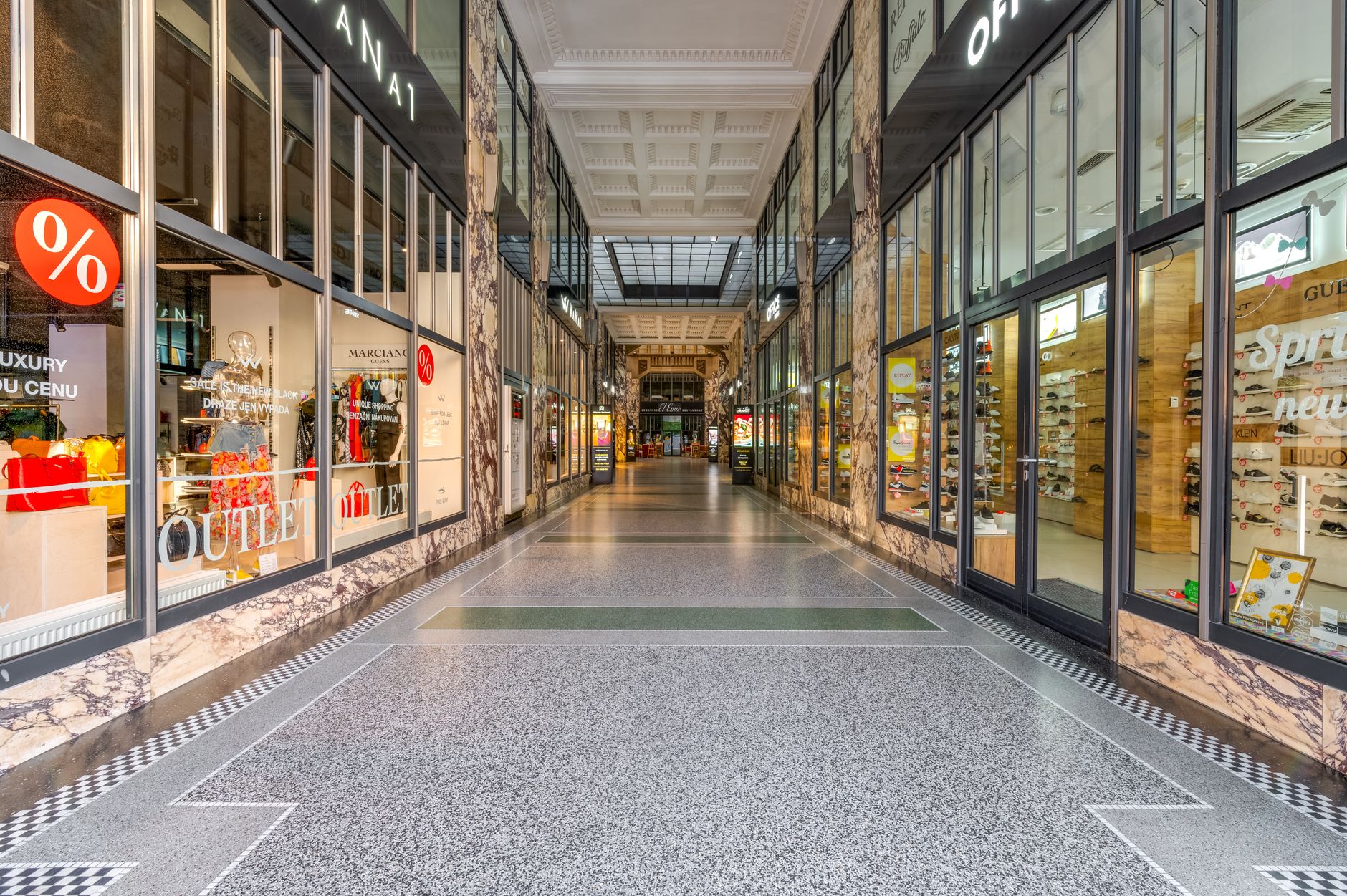 Wide corridor inside an outlet shopping center with polished tile flooring