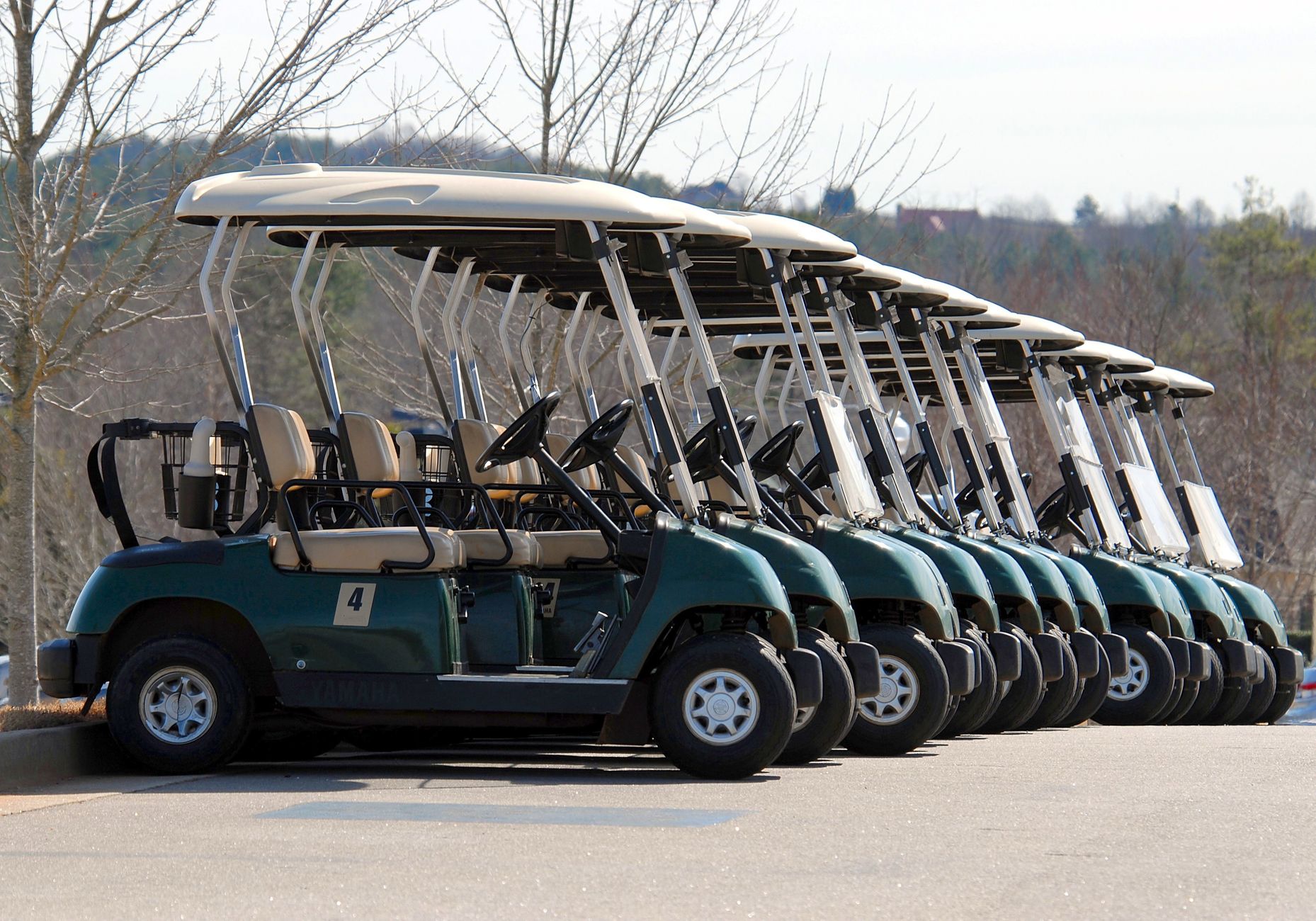 Golf carts parked in rows beside a maintenance building at dusk.