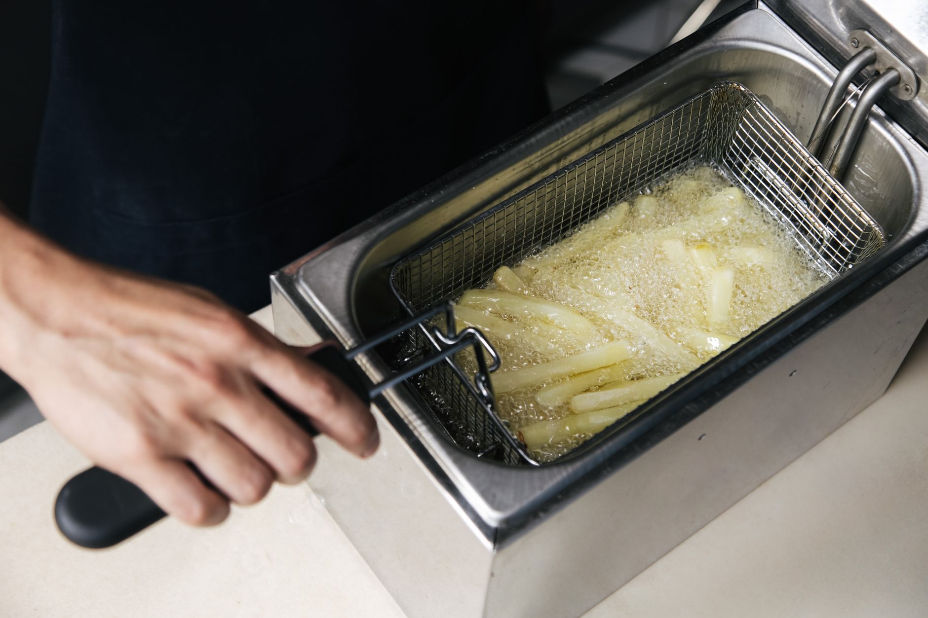 A stainless steel deep fryer in a commercial kitchen, where an automated cooking system would handle repetitive tasks.