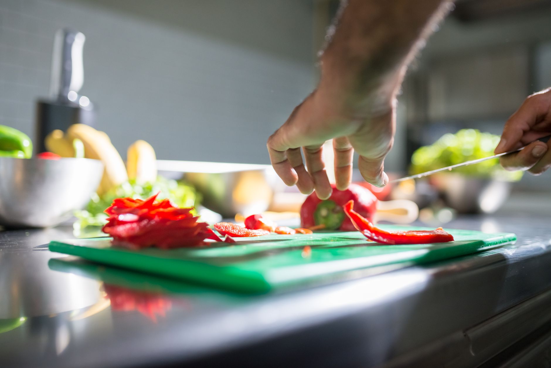 A chef's prep station in a commercial kitchen showing neatly chopped vegetables on a cutting board.