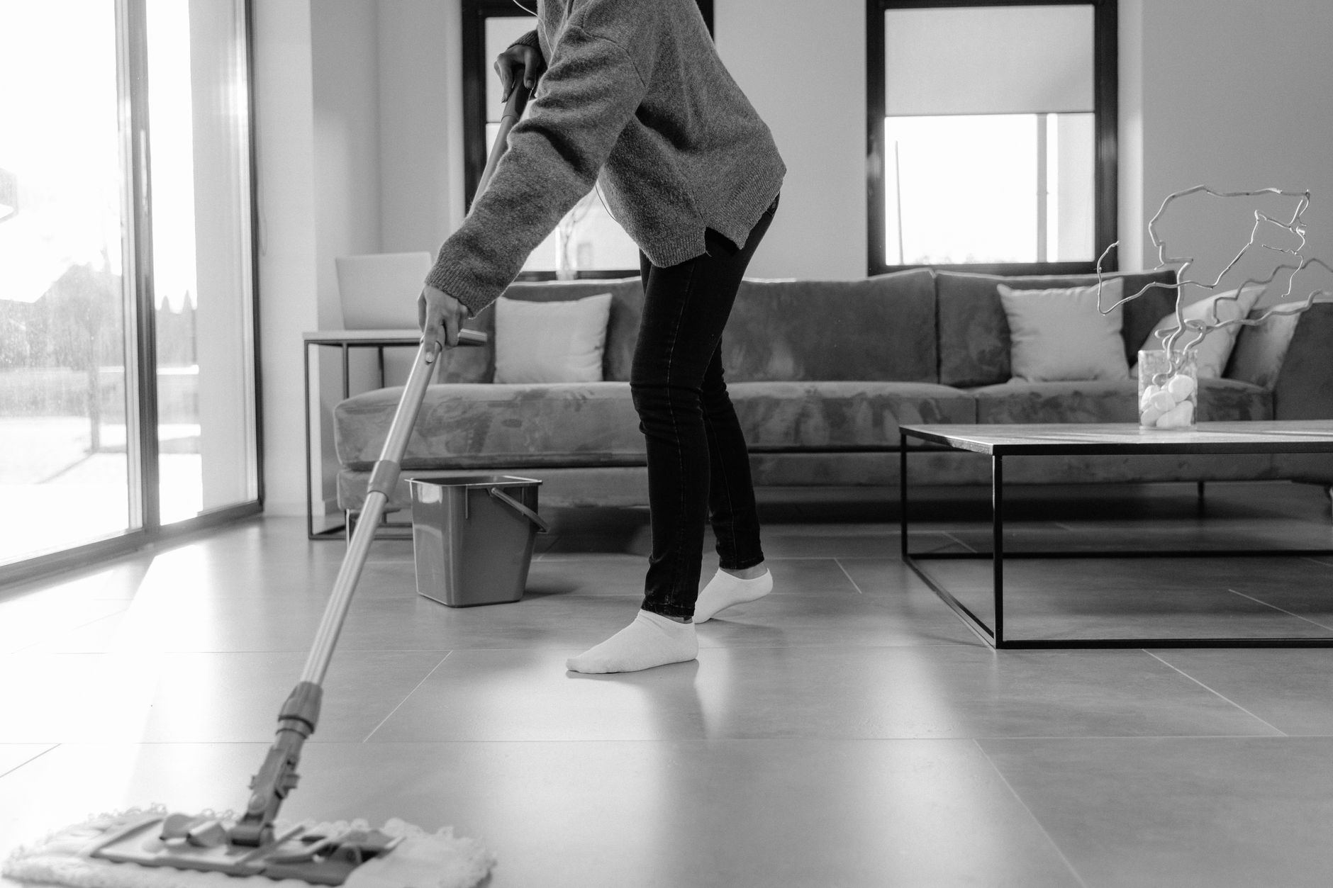 A maintenance worker mopping a floor, representing the human labor that efficient robotics and zero-maintenance batteries help to minimize.
