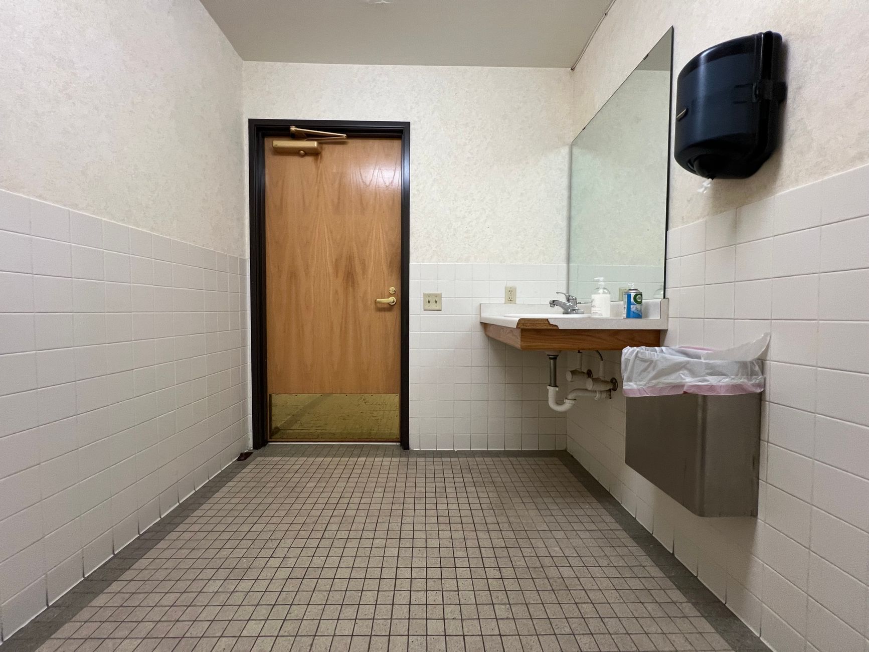 A tiled restroom approach in a commercial facility, highlighting the wet hard-floor zones that drive cleaning decisions.