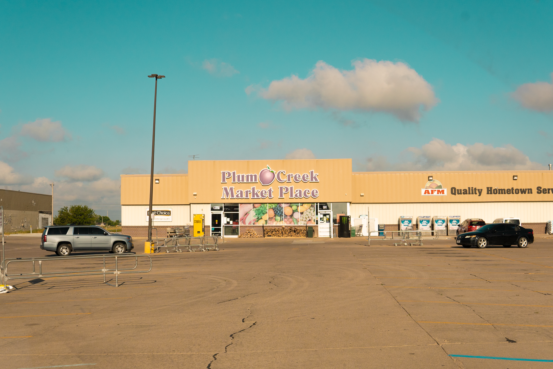 A supermarket parking lot with shopping carts lined near a return corral on asphalt.