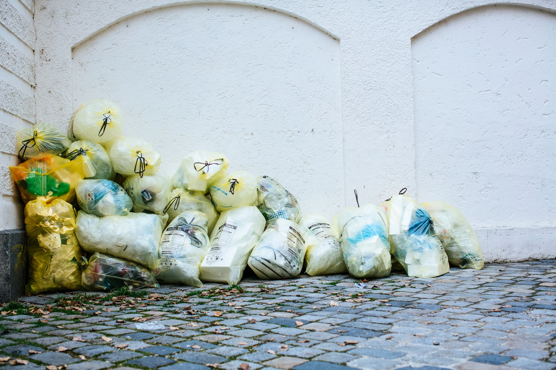 Piles of clear bags filled with trash and recycling sit in a stadium concourse, awaiting transport after a large event.