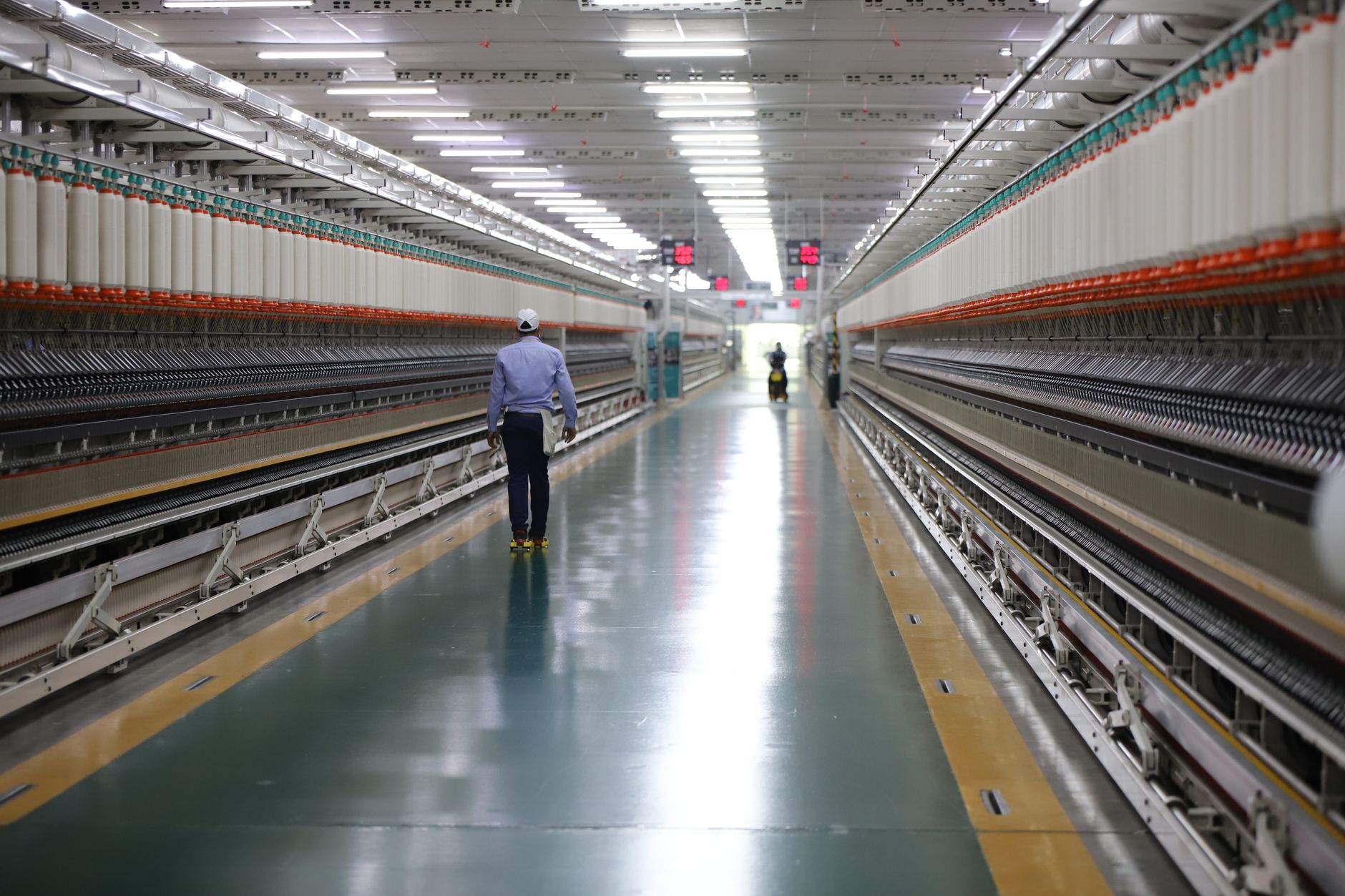 A worker travels through a long industrial corridor while completing a manual inspection route.