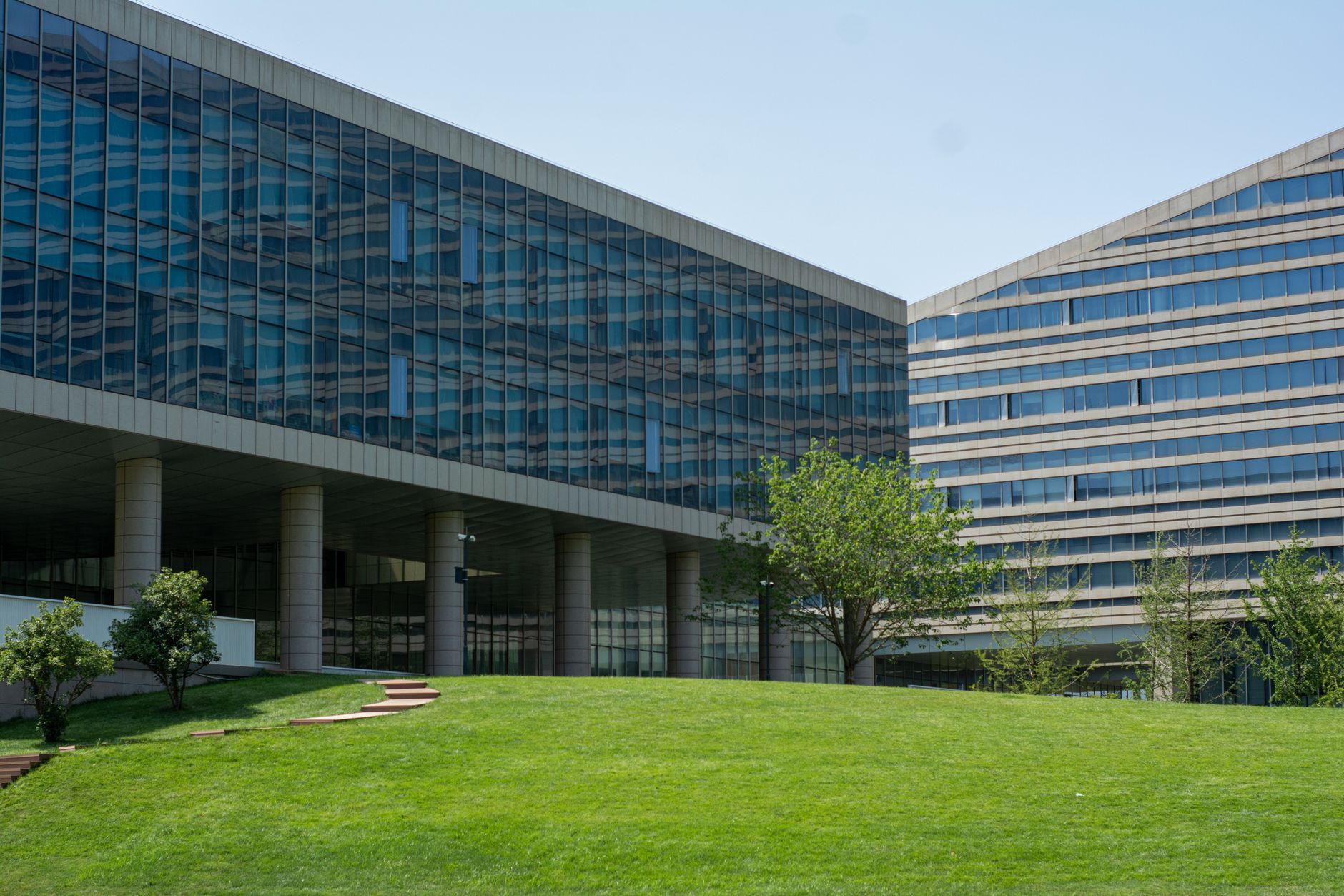 Wide green lawn and glass office buildings on a corporate business park campus.