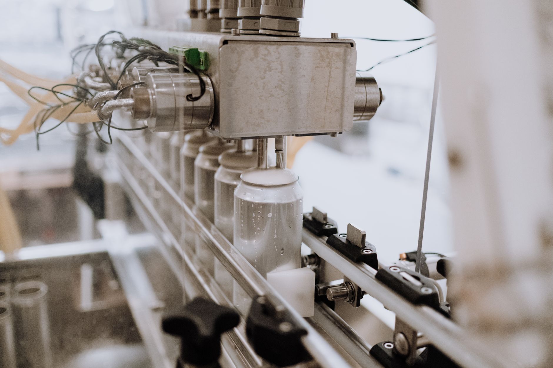 Close-up of beer cans moving down a metal conveyor belt, representing increased and consistent throughput.
