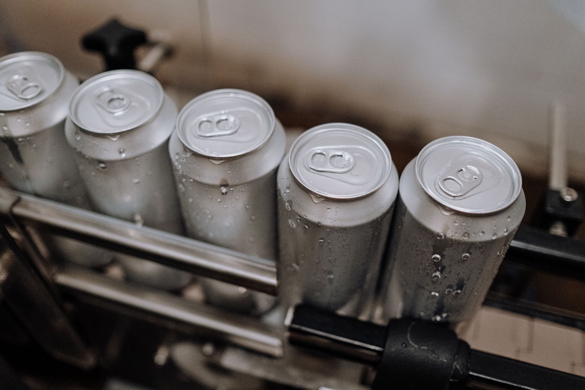 Cases of craft beer move down a conveyor belt on a packaging line inside a brewery warehouse.