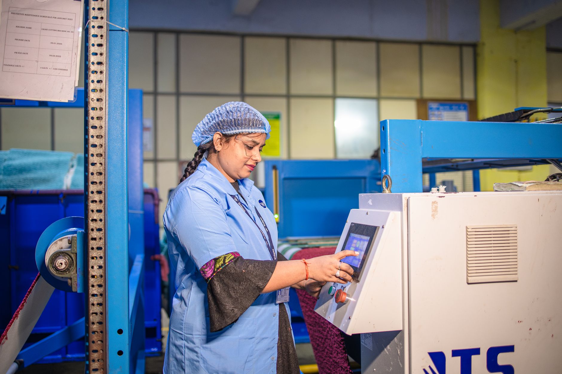 A machine operator tends to a piece of industrial equipment, representing the repetitive reaches and standing required for machine tending.