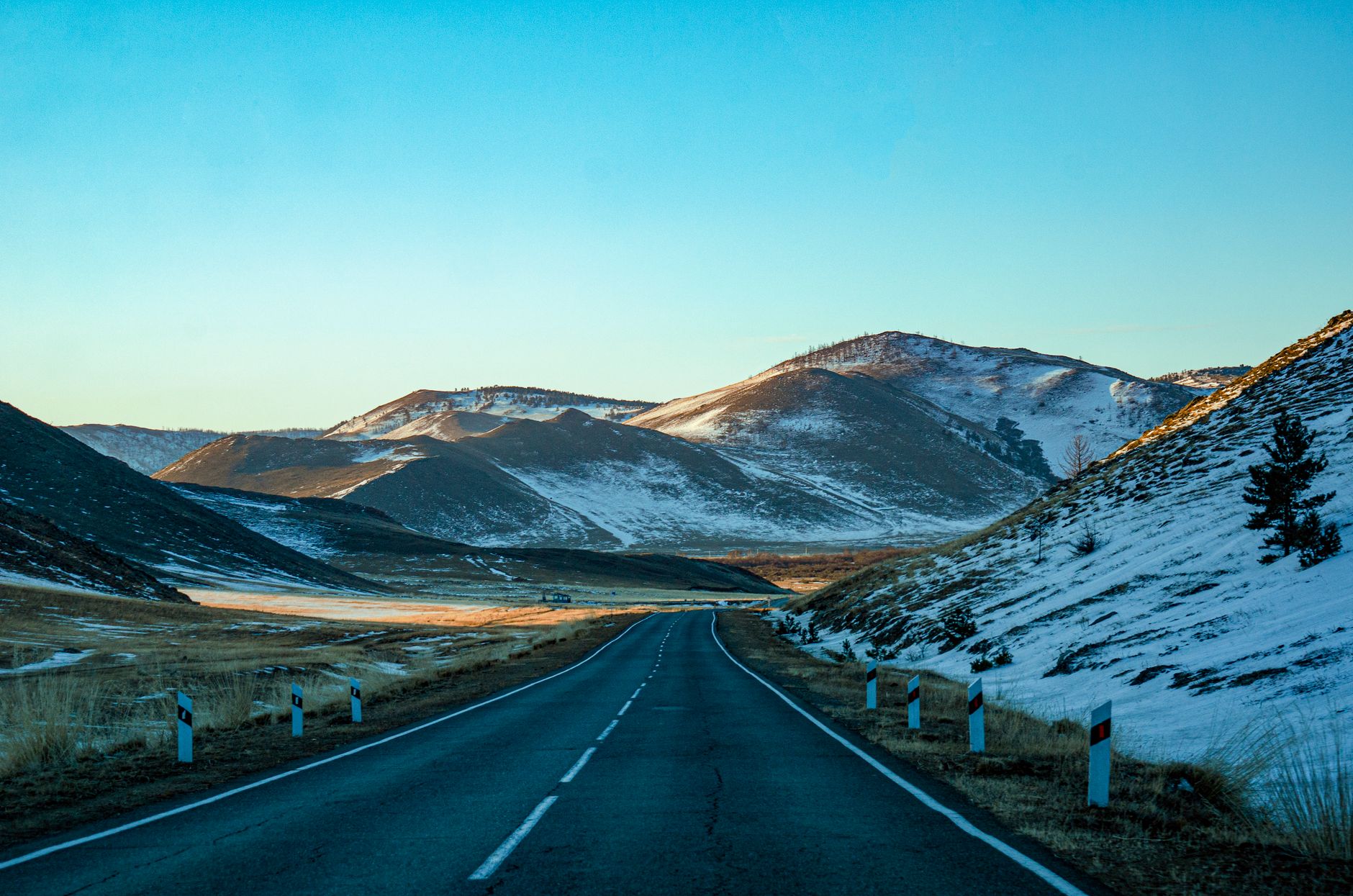 Snow-lined highway through a mountain valley suggesting seasonal travel