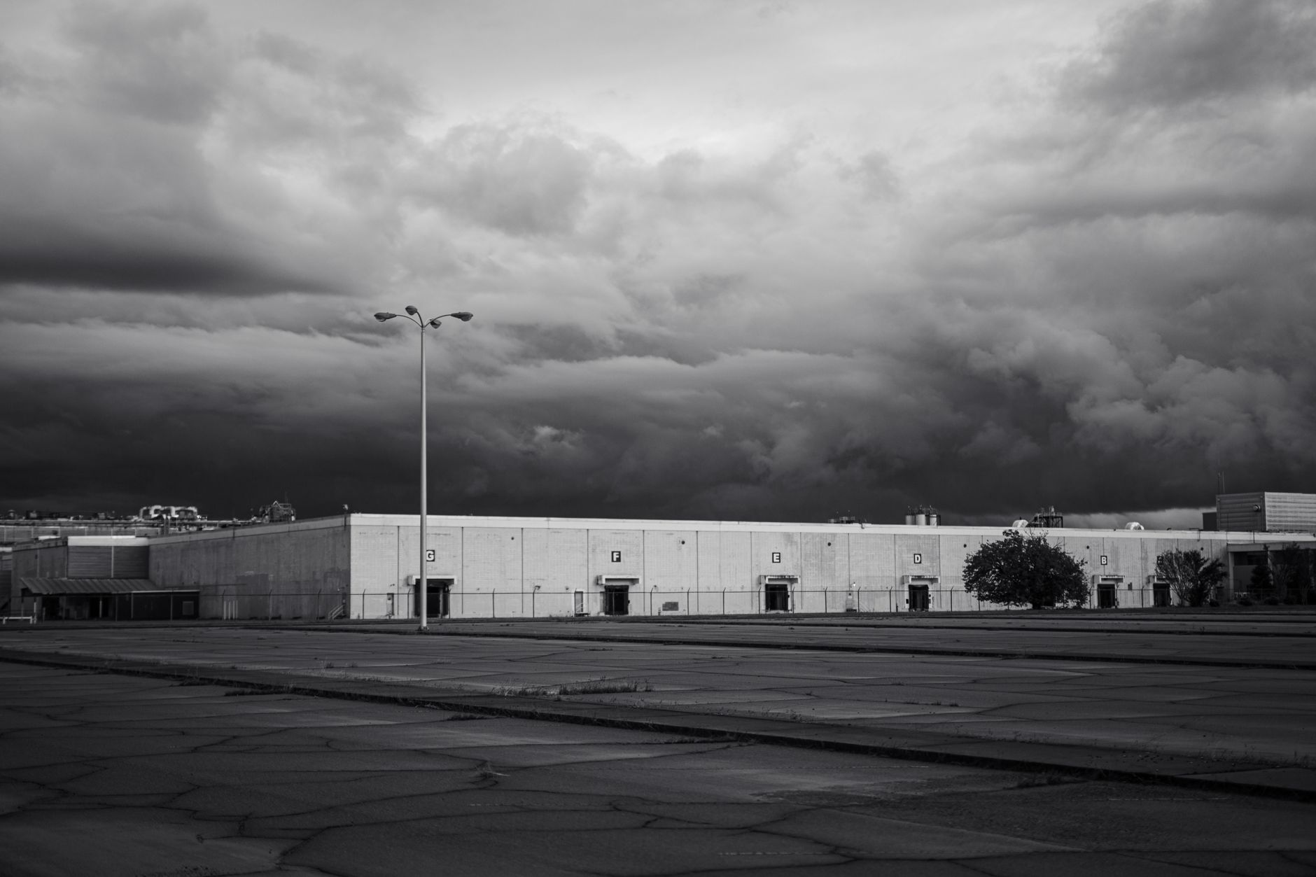 Storm clouds over a commercial parking lot where outdoor patrol and delivery robots must park before lightning arrives.