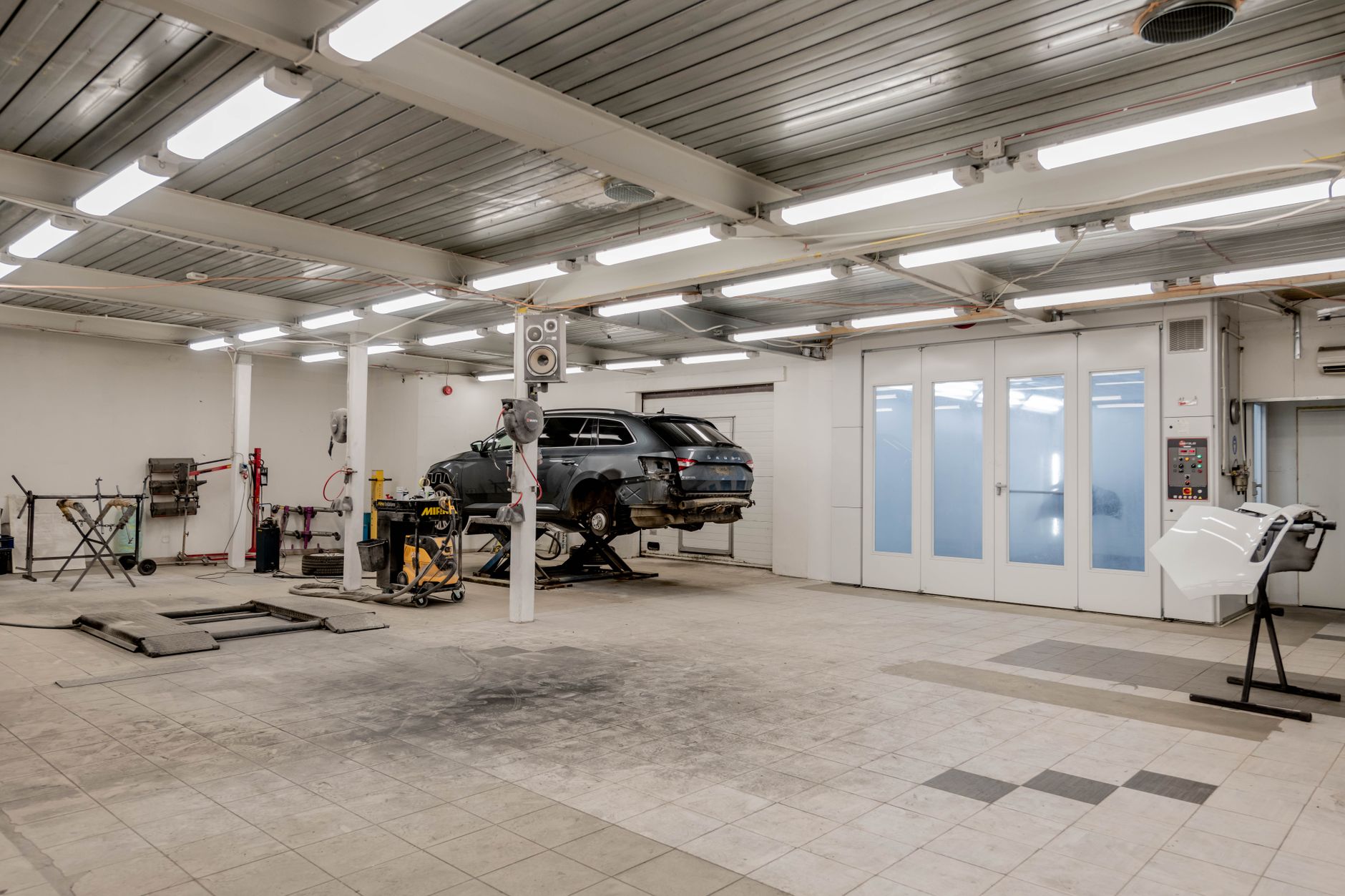 A sealed concrete aisle inside a service shop where scuff marks show along the daily traffic path.