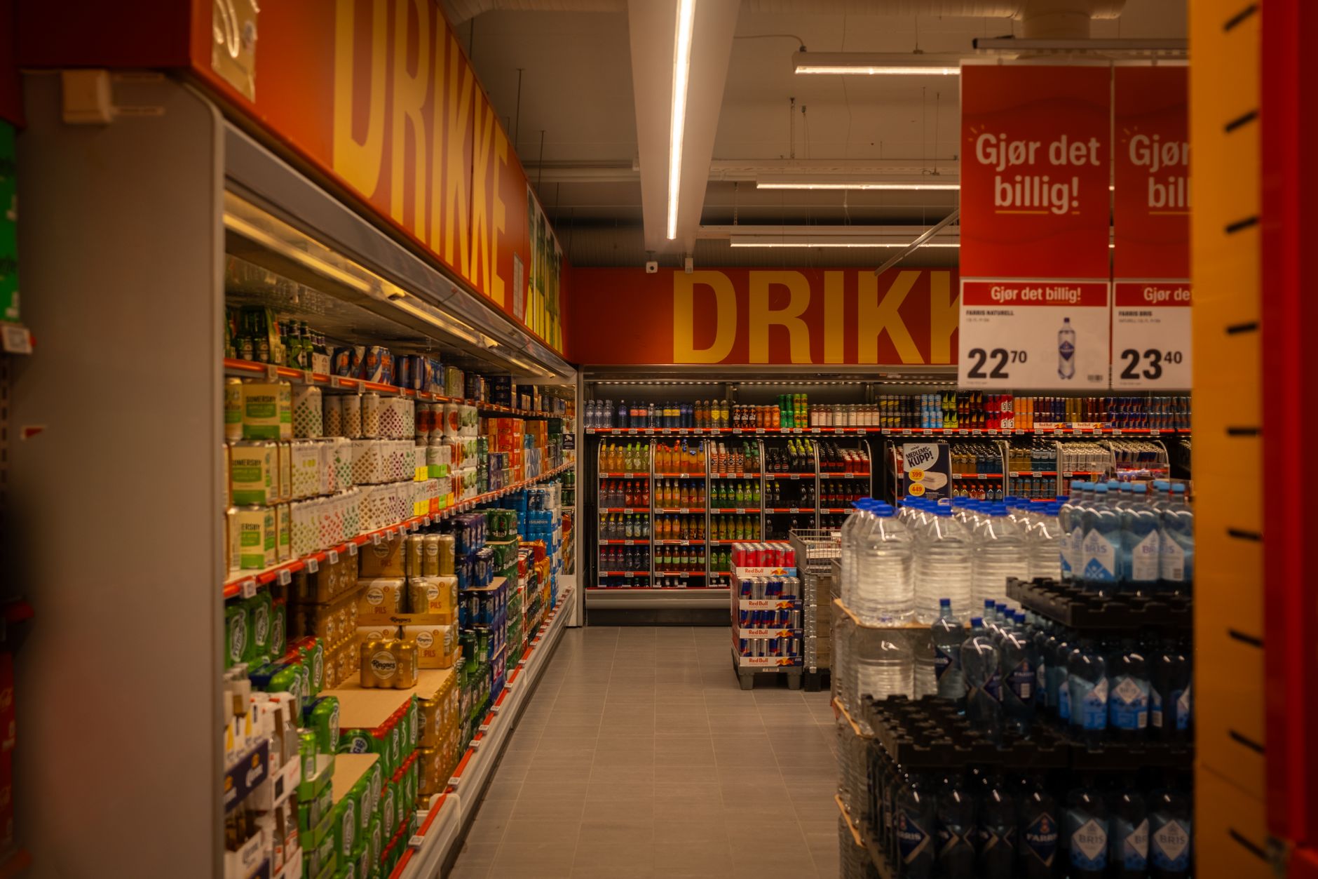 Empty grocery aisle with polished floors under overhead lights.
