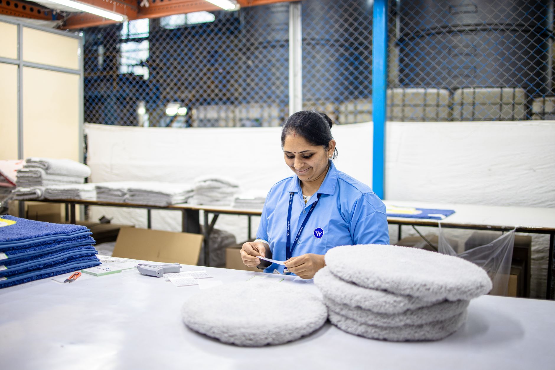 A factory employee repeatedly packs boxes at a fixed workstation where ergonomic exposure can concentrate.