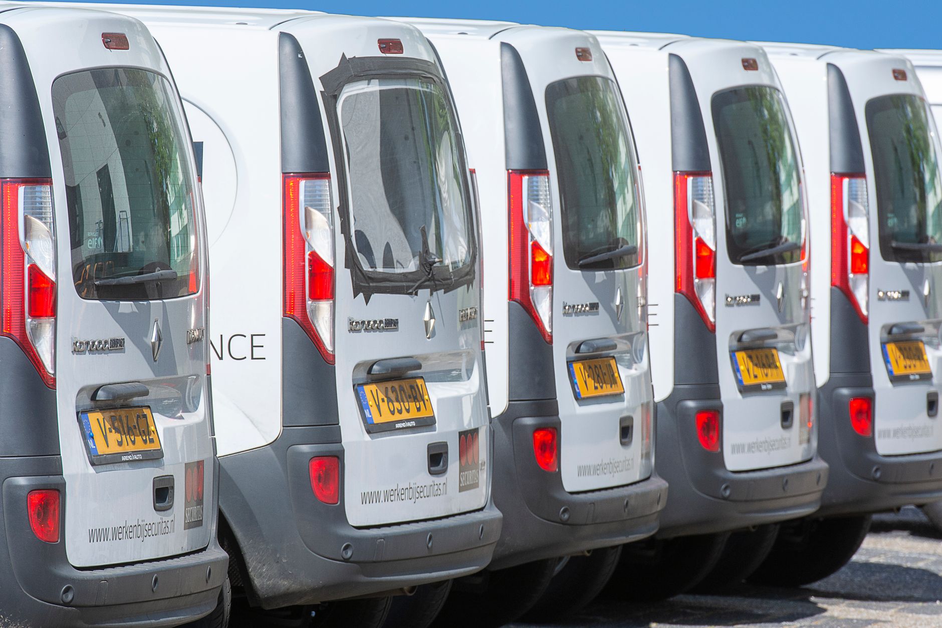 A row of service vans in a parking lot, illustrating the field-service coverage and dispatch muscle large retail rollouts require.