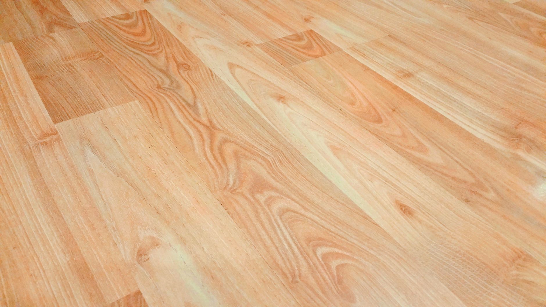 Workers laying wide luxury vinyl planks across a bright commercial retail floor during finish-out.