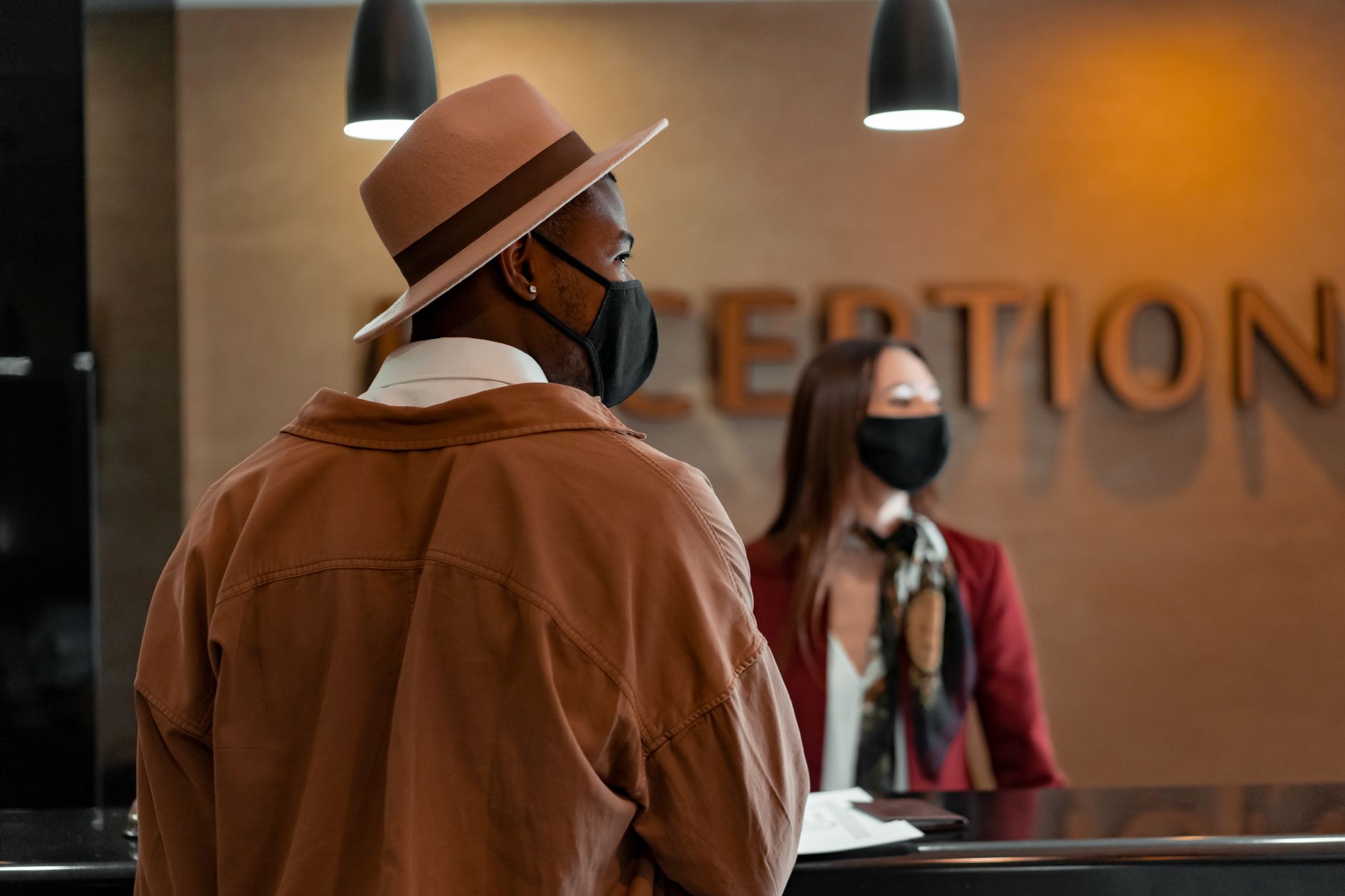 Front desk staff assisting guests at a hotel reception, showing how little spare capacity hotel teams have during live operations.