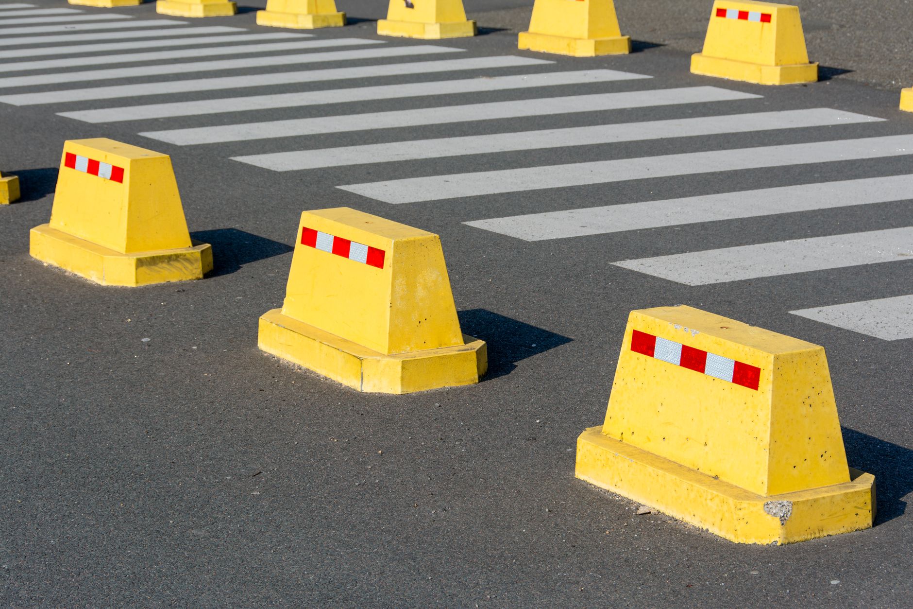 Bright yellow safety lines are painted on a clean concrete warehouse floor, indicating the designated pathways for mobile robots as defined by AMR safety standards like ANSI/A3 R15.08.