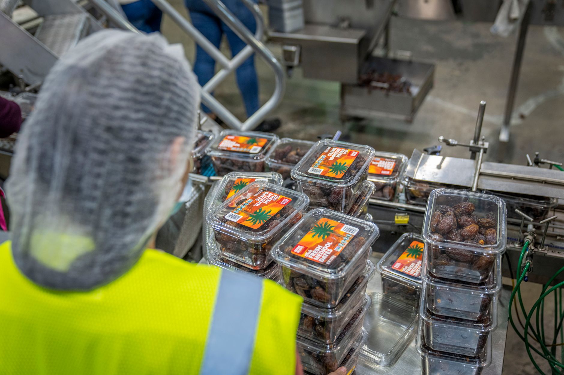 Workers handle packaged goods on a busy food production floor.