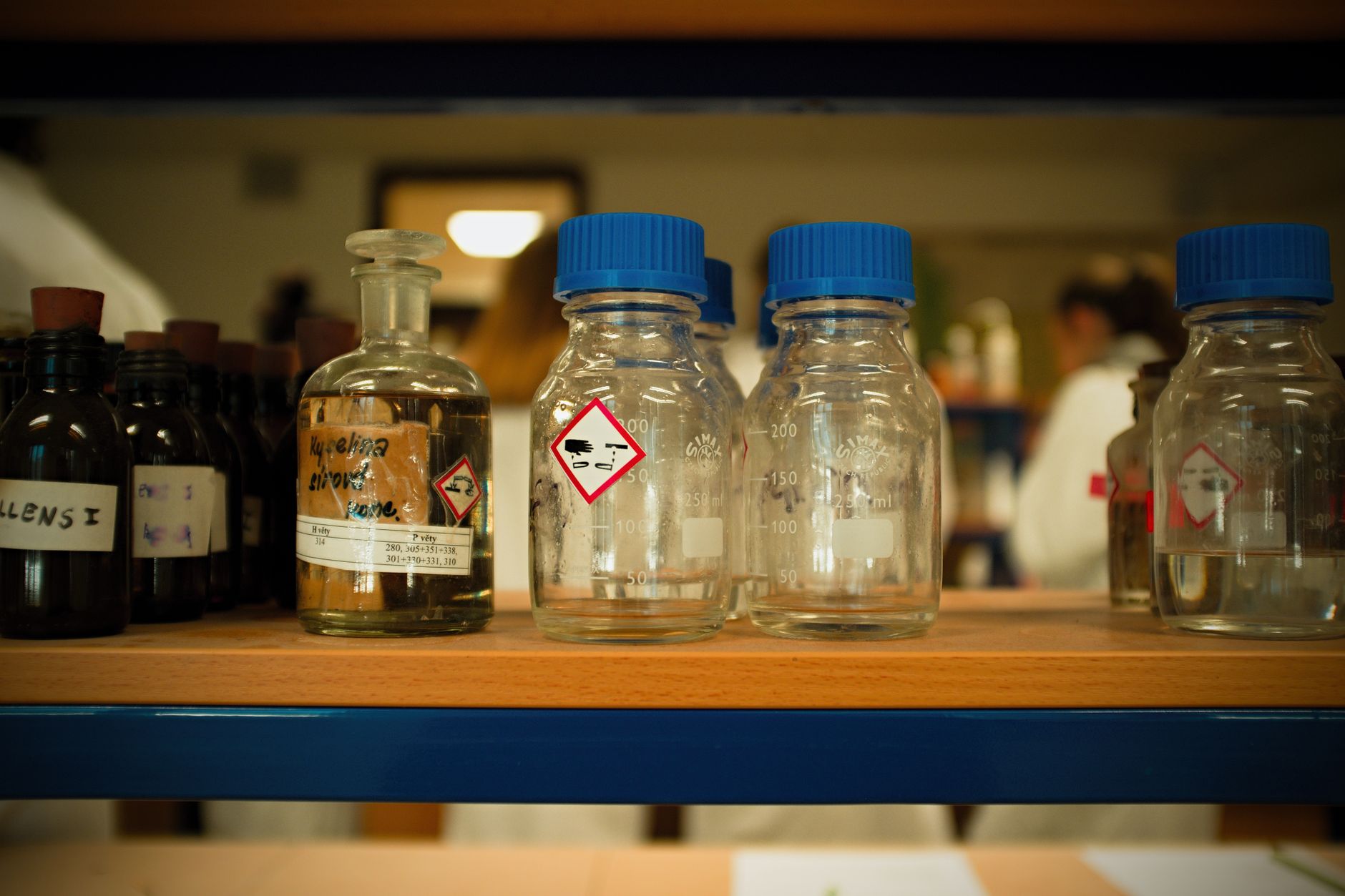 A close-up of hazard communication labels on chemical containers in a storage area, highlighting the need for clear warnings as mandated by OSHA.