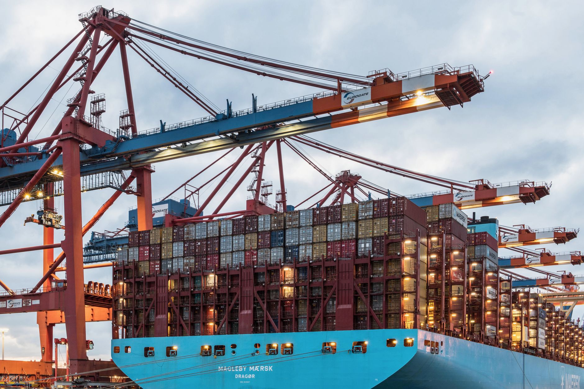 Workers unload mixed cartons from a shipping container at a warehouse receiving dock.