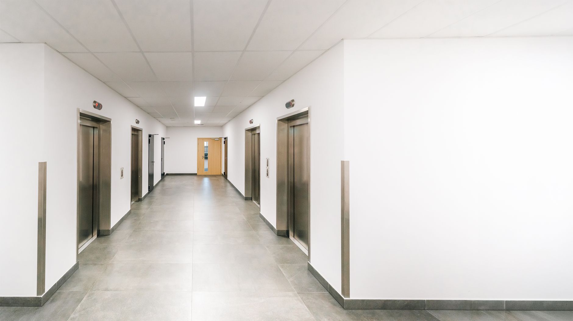 A hospital elevator lobby with clear circulation space, highlighting the choke points and safety checks that matter when transport routes are reviewed.