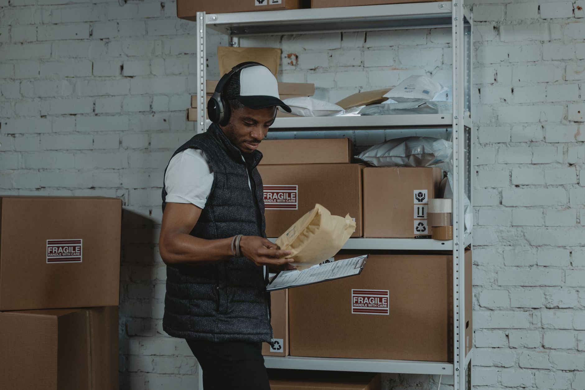 A worker moves through a compact stockroom lined with shelving and boxed inventory.