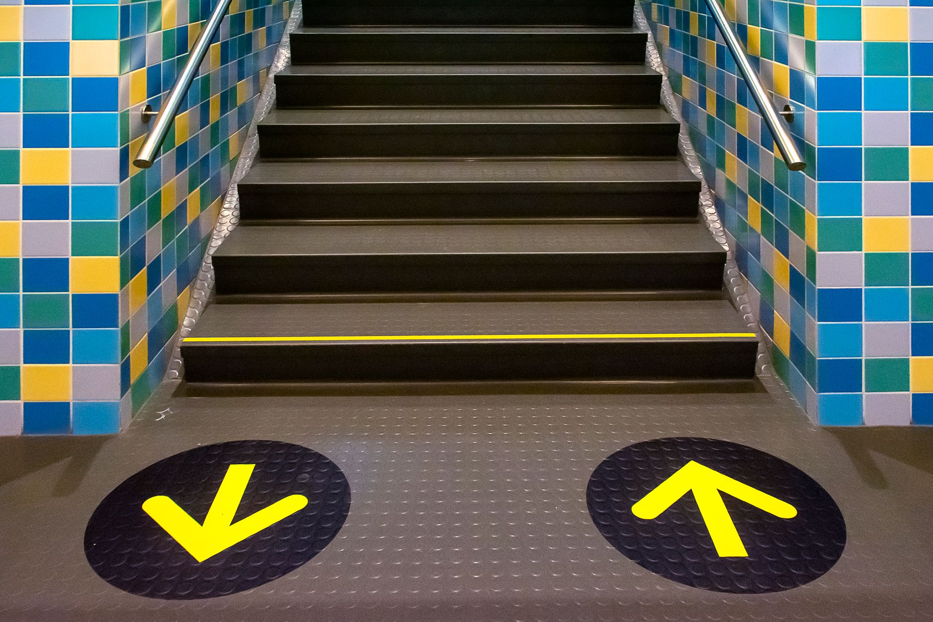 Yellow directional arrows painted on a clean concrete warehouse floor, representing the rules and standards that allow for coordinated movement.