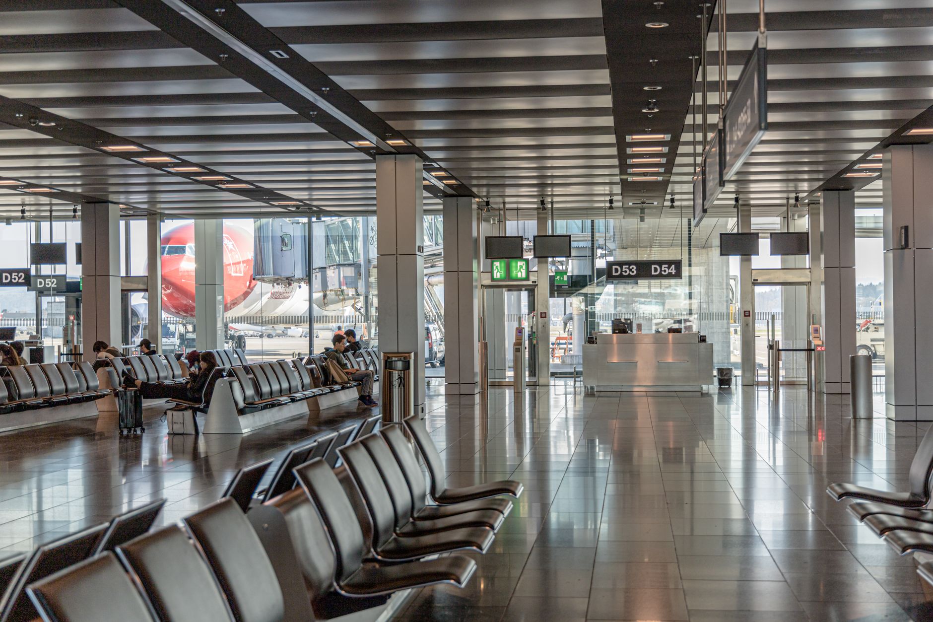 Passengers seated near an airport gate, reinforcing that public cleanliness programs have to work smoothly around live traveler flow.