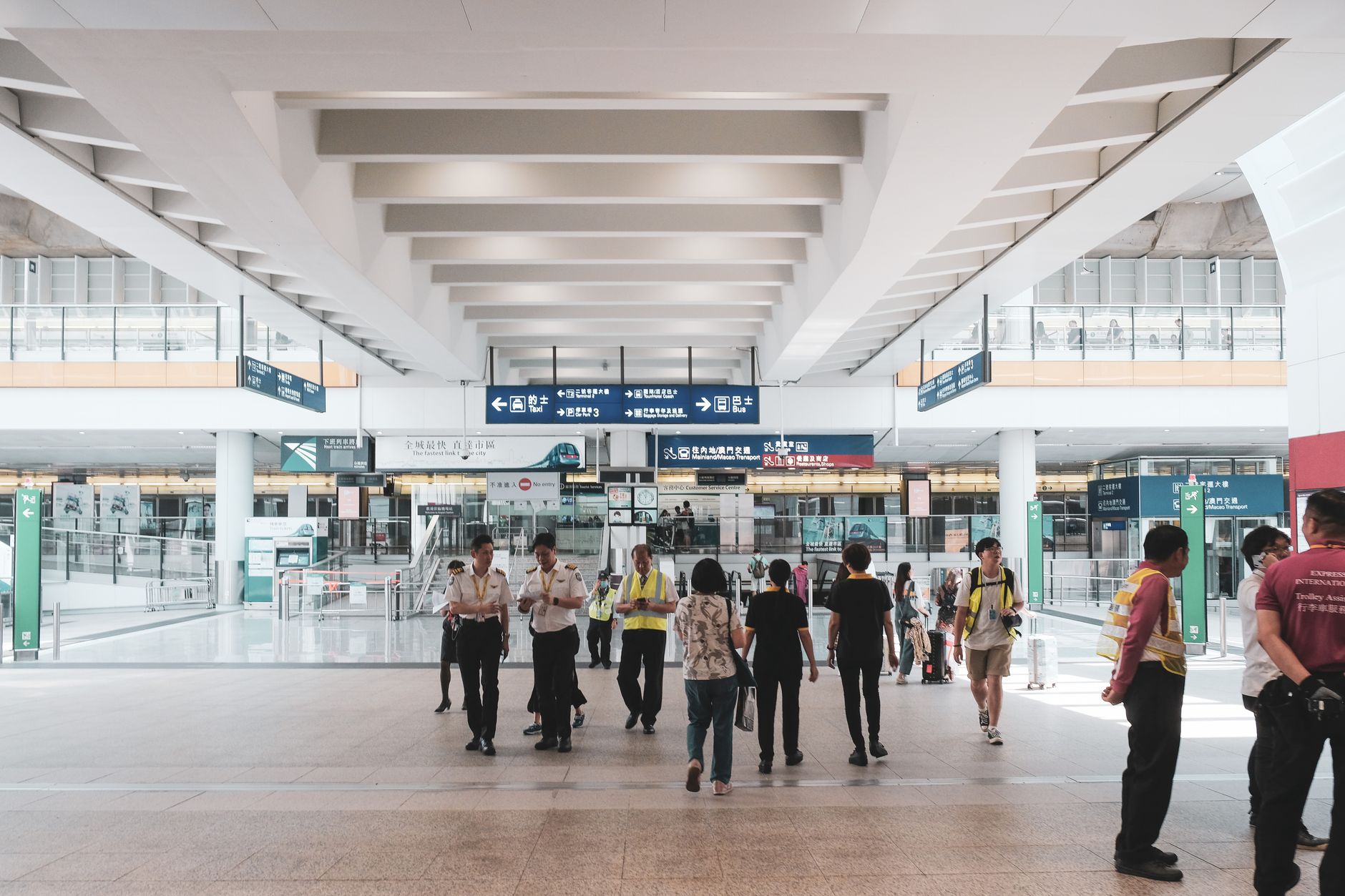 A broad passenger-terminal concourse with open floor space, clear sightlines, and travelers moving through the hall.