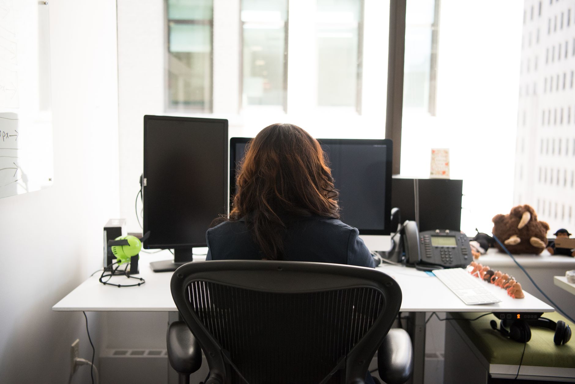 Supervisor at a desk with monitors, representing in-house staff pausing floor work for remote assist.