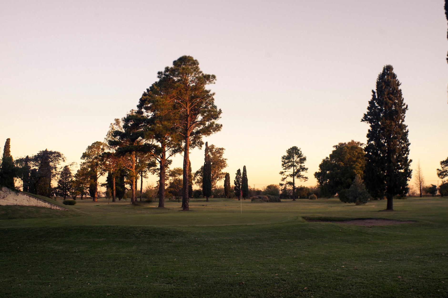 Empty golf fairway at dawn with soft light across the turf before players arrive.